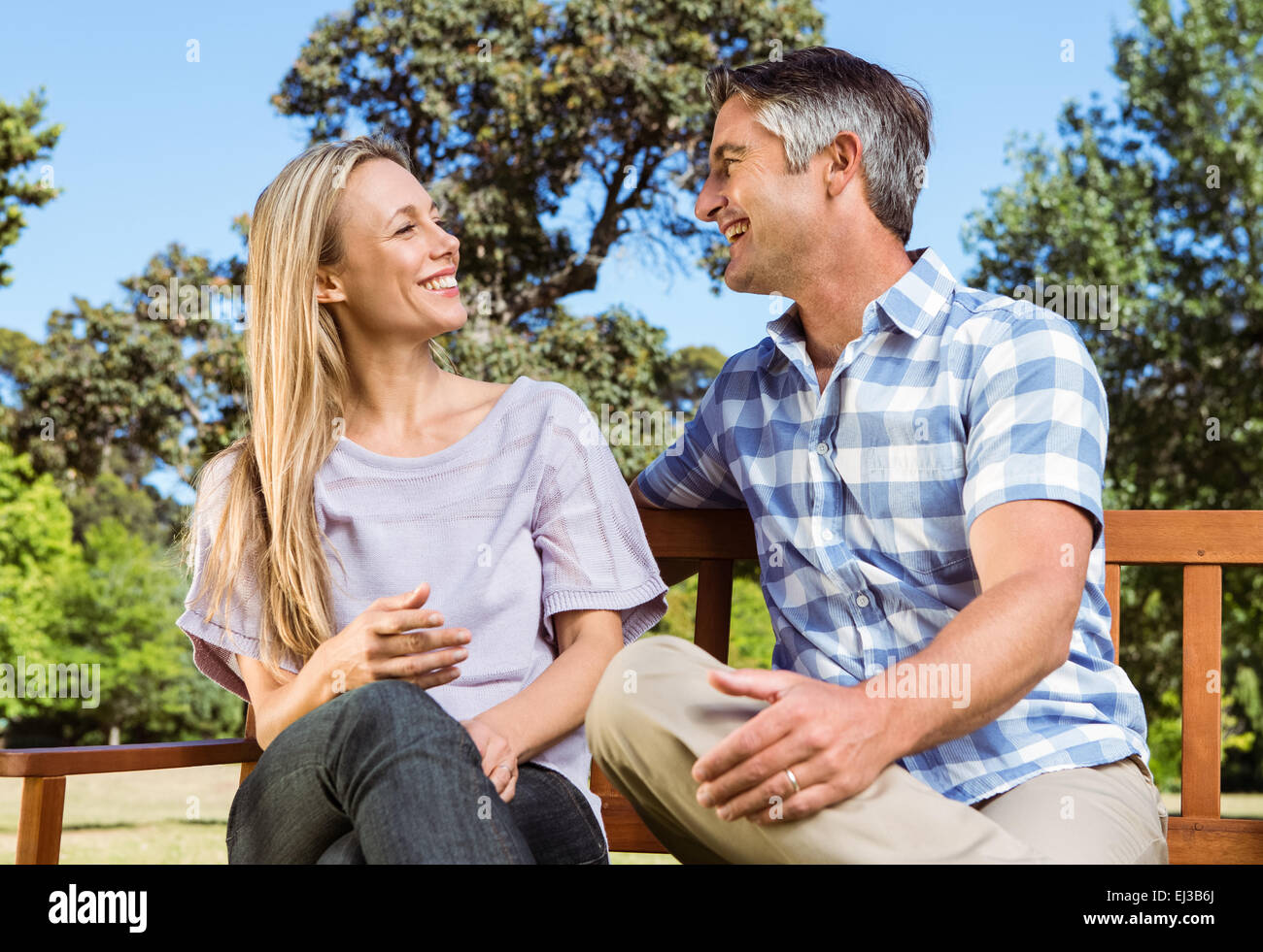 Couple relaxing in the park on bench Stock Photo - Alamy