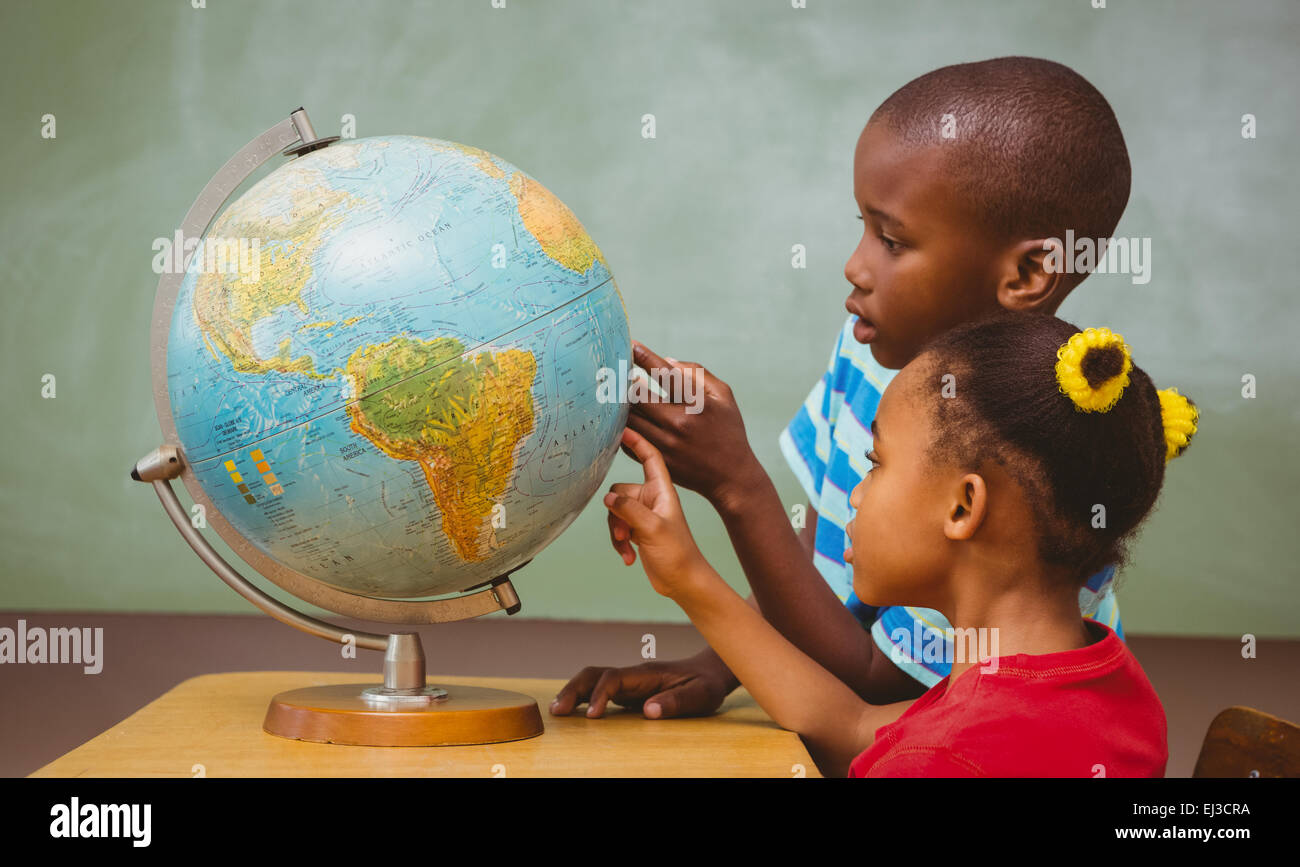 Kids pointing at globe in classroom Stock Photo - Alamy