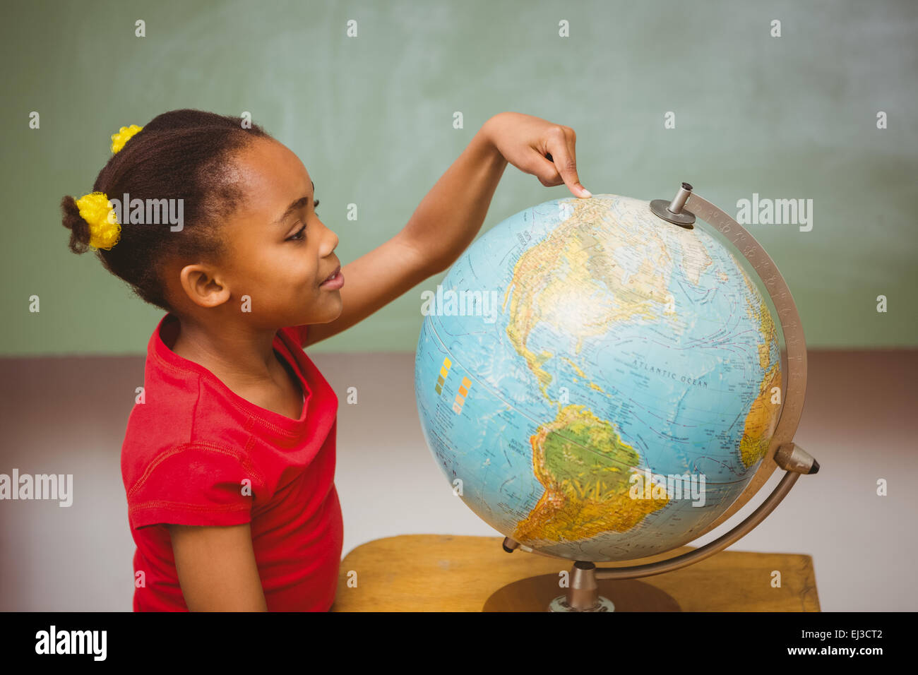 Little girl pointing at globe in classroom Stock Photo - Alamy
