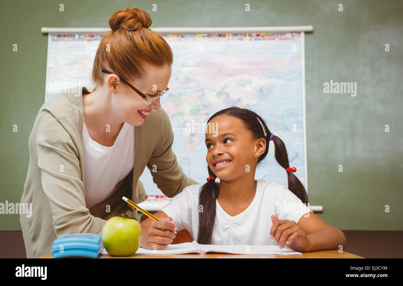 Teacher assisting girl with homework in classroom Stock Photo - Alamy