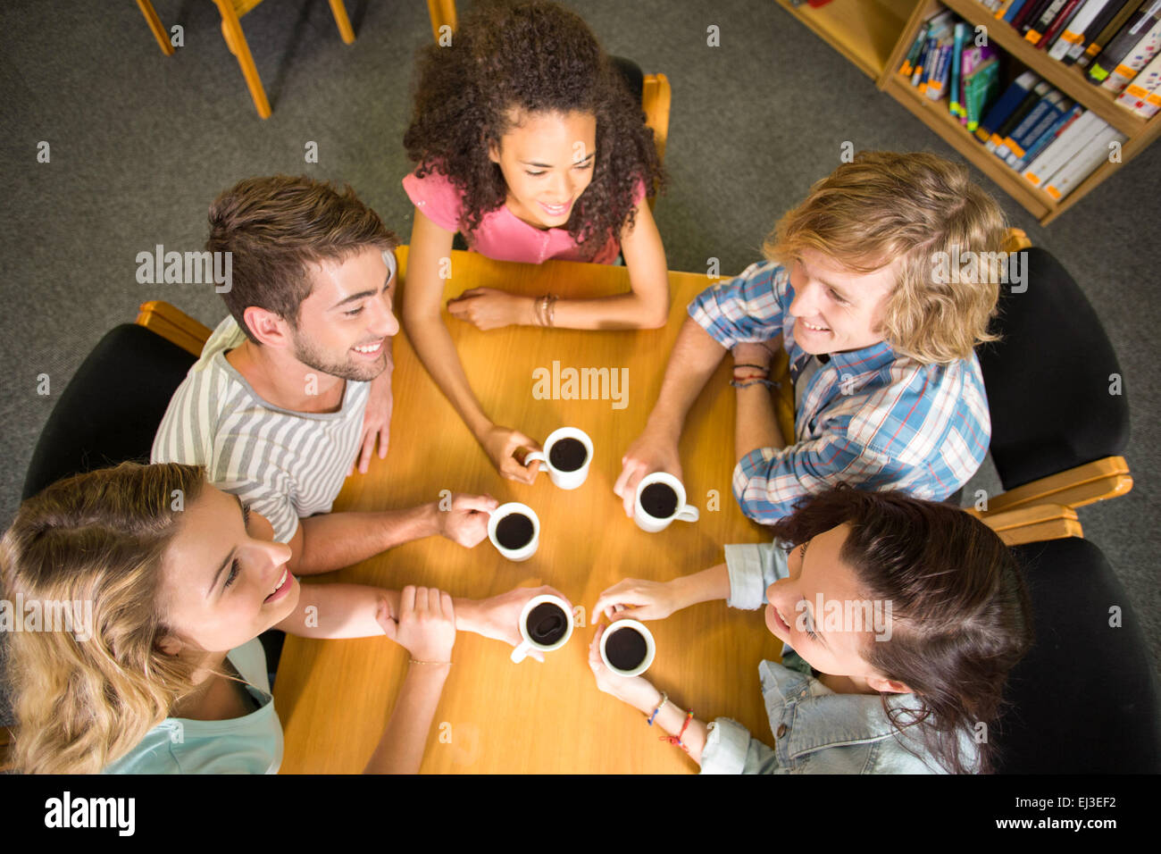 College students holding coffee mugs on table Stock Photo Alamy