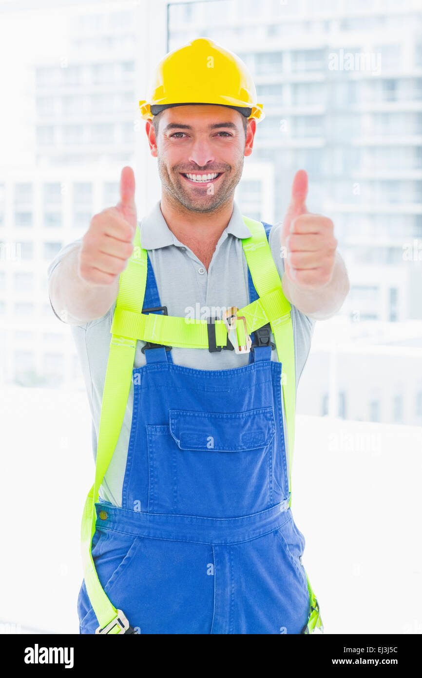Worker wearing safety harness while gesturing thumbs up Stock Photo