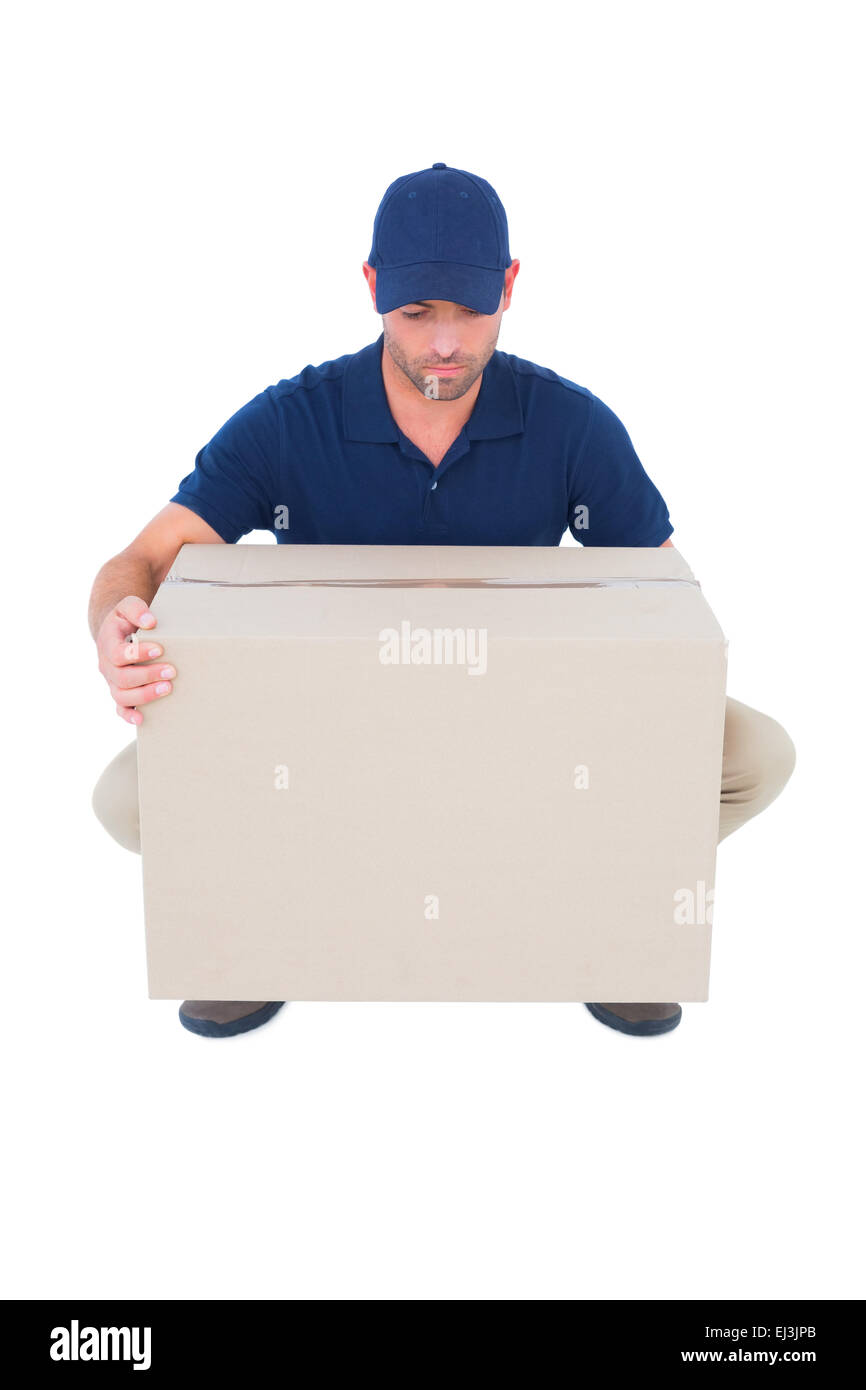 Delivery man crouching while picking cardboard box Stock Photo