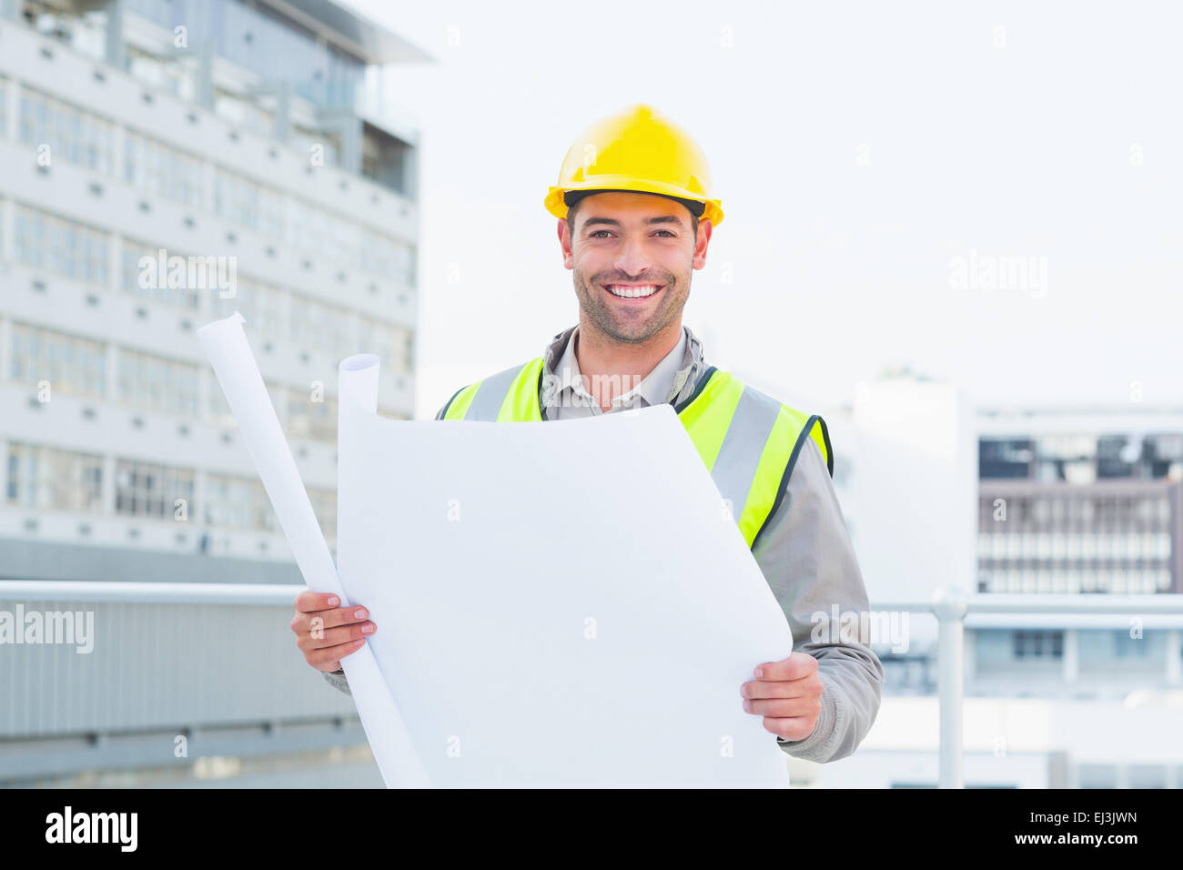 Happy architect holding blueprints outside building Stock Photo - Alamy