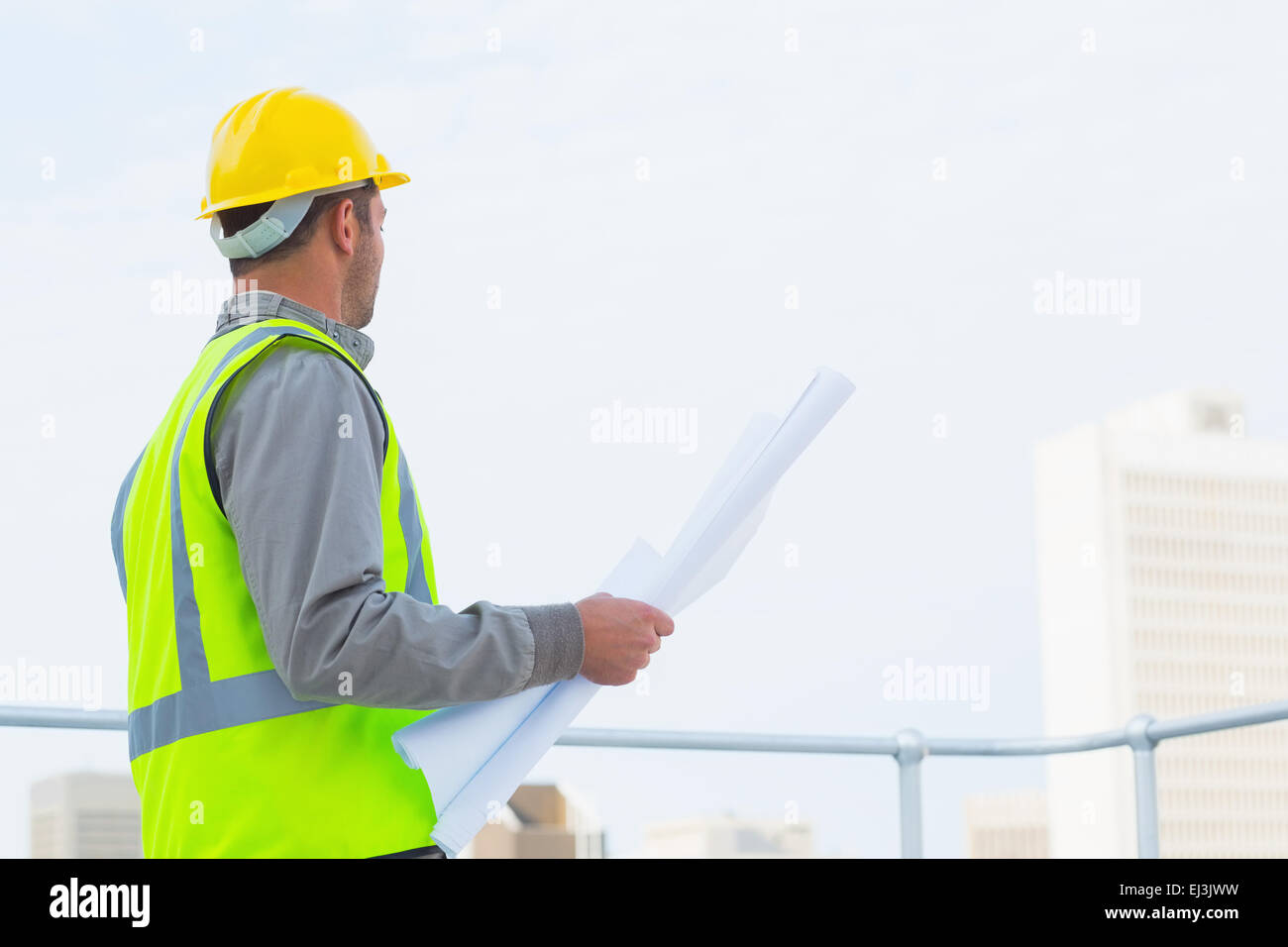 Architect in protective workwear holding blueprints outdoors Stock Photo