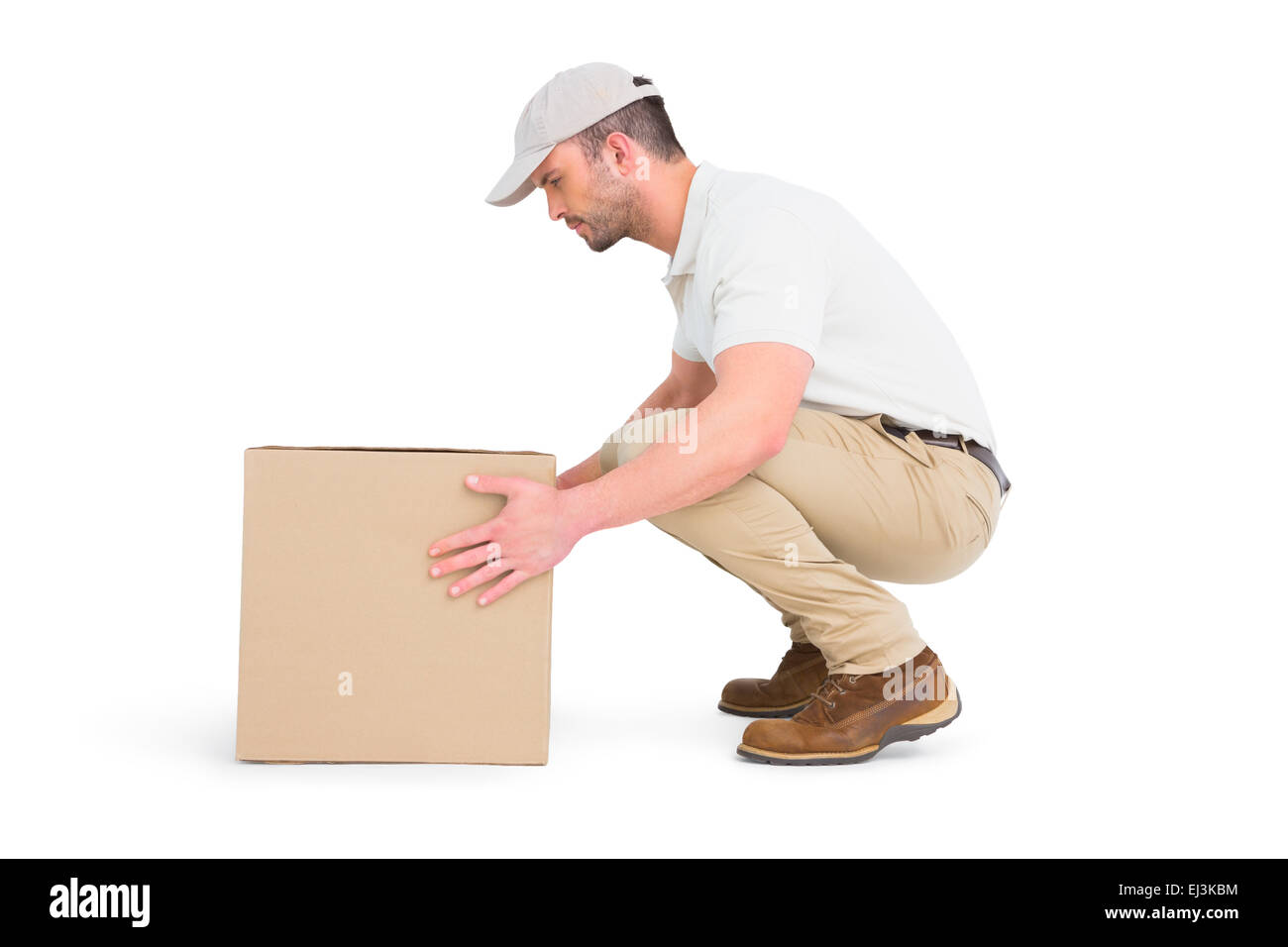 Delivery man crouching while picking cardboard box Stock Photo
