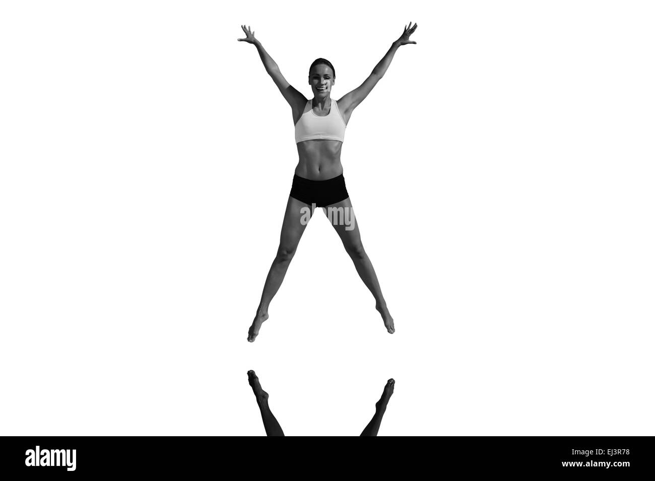 Composite image of fit woman jumping with arms out Stock Photo