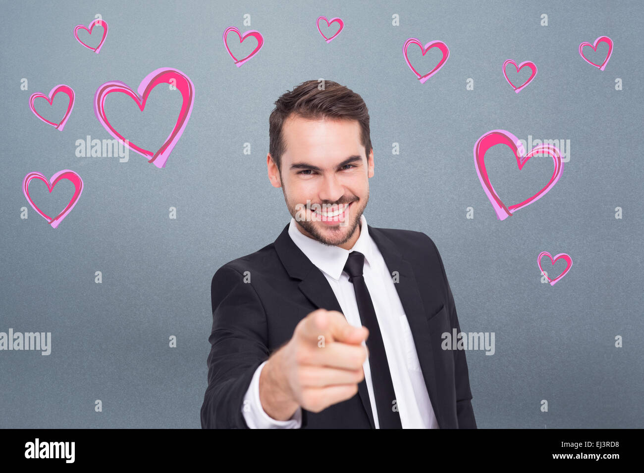 Composite image of happy businessman pointing at camera Stock Photo