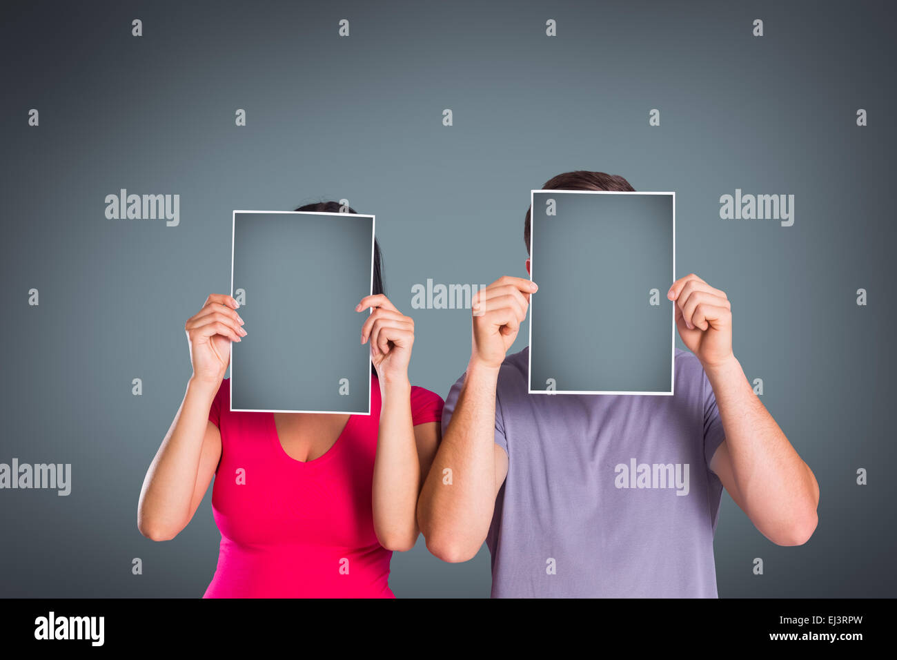 Composite image of couple covering faces with paper Stock Photo
