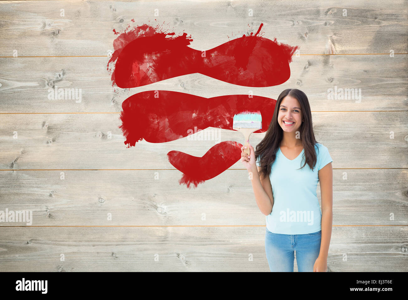Composite image of happy young brunette holding paintbrush Stock Photo
