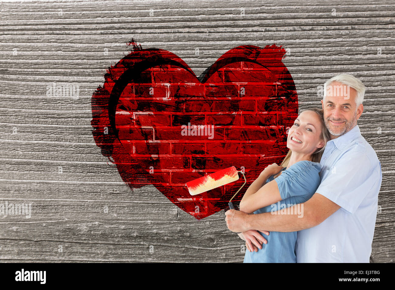Composite image of happy couple hugging and holding paint roller Stock Photo