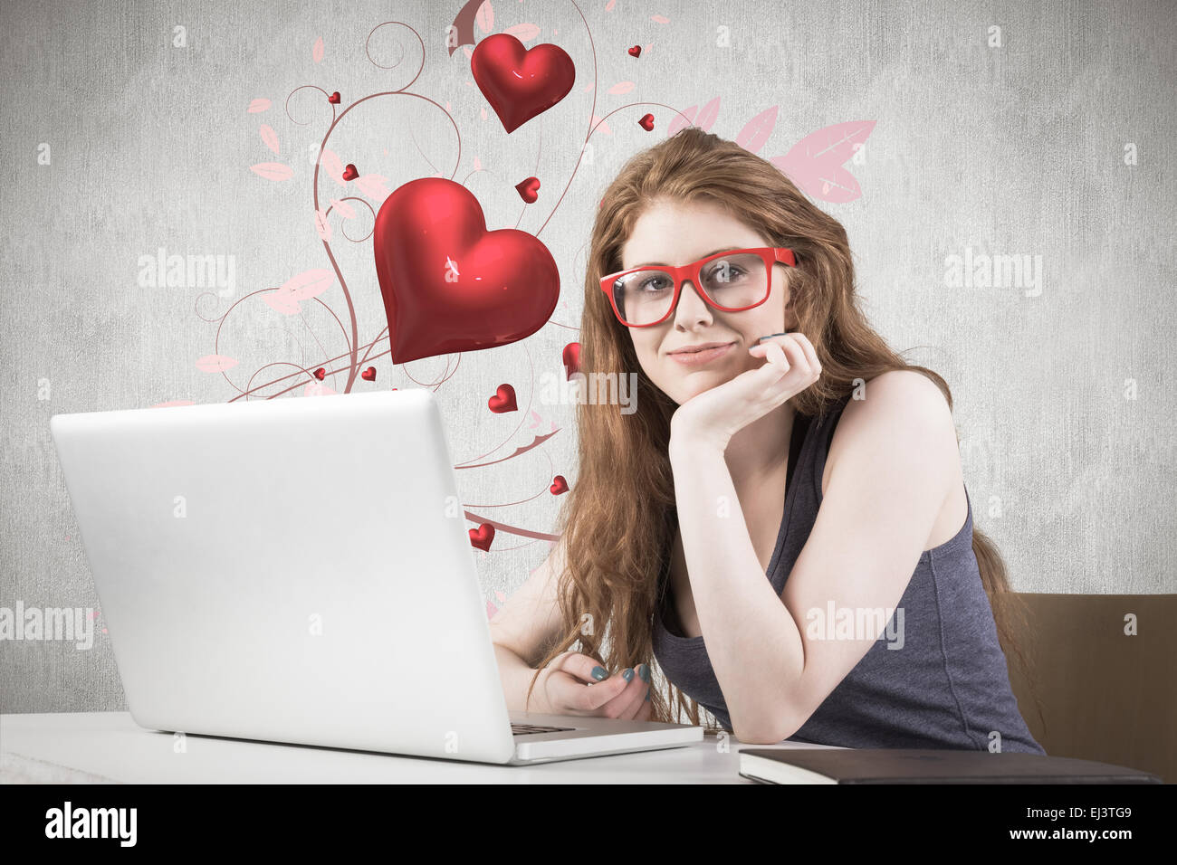 Composite image of pretty redhead working on laptop Stock Photo - Alamy