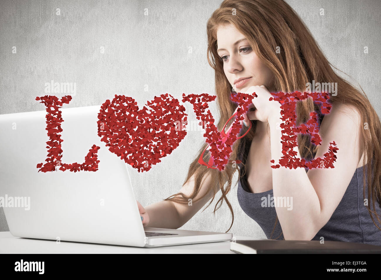 Composite image of pretty redhead working on laptop Stock Photo - Alamy