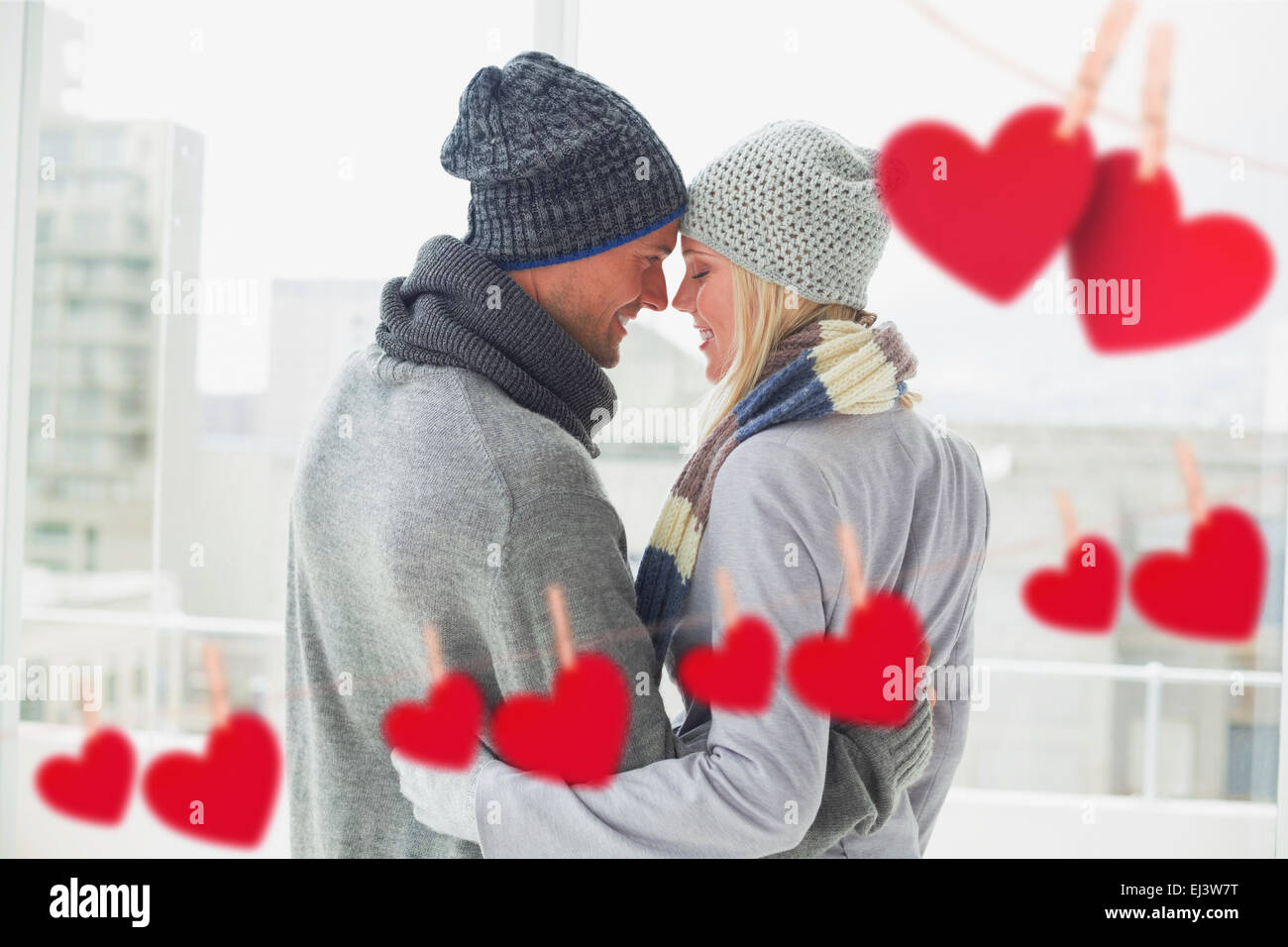 Composite image of cute couple in warm clothing hugging Stock Photo - Alamy