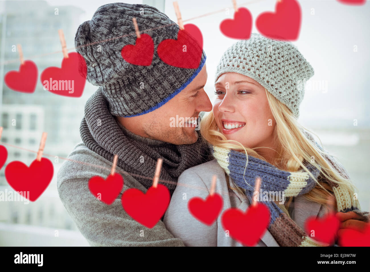 Composite image of cute couple in warm clothing smiling at each other ...