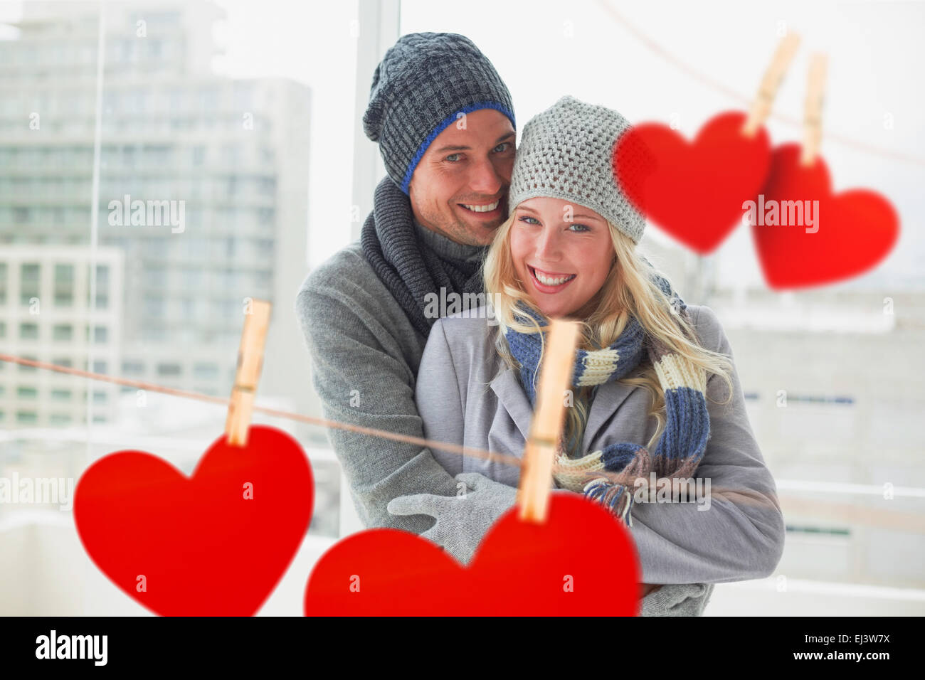 Composite image of cute couple in warm clothing smiling at camera Stock Photo