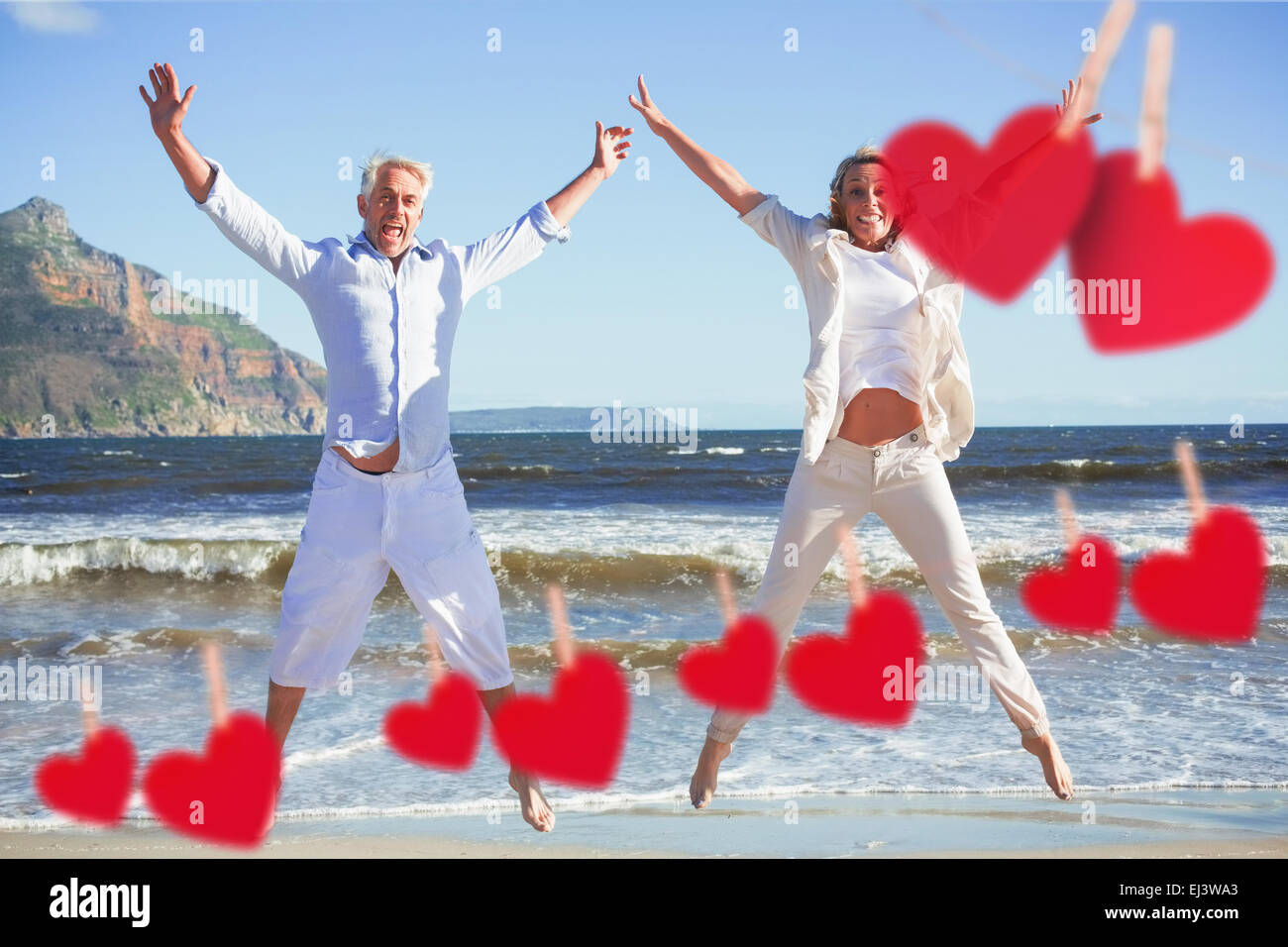 Composite image of happy couple jumping on the beach together Stock Photo