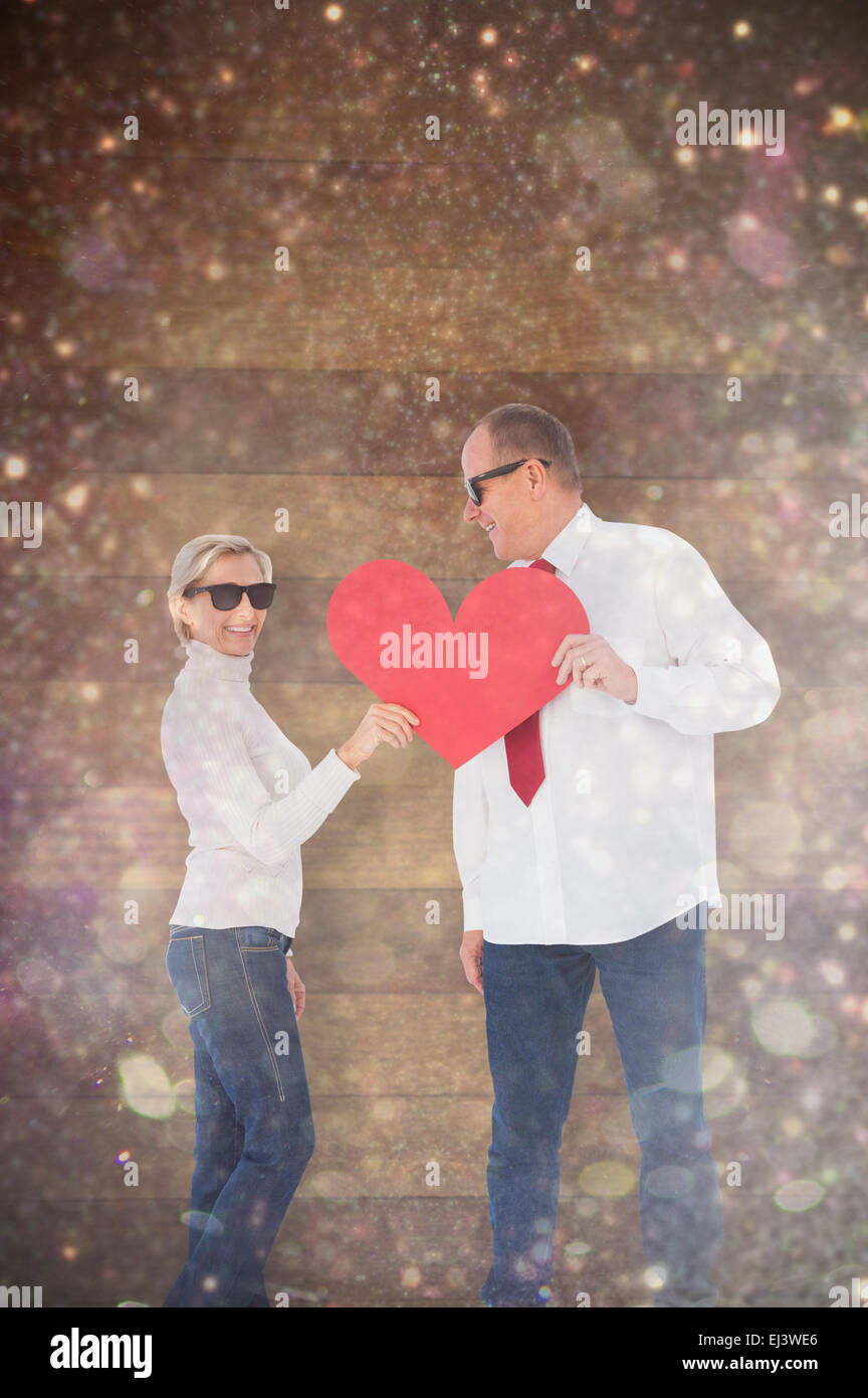 Composite image of older affectionate couple holding red heart shape Stock Photo