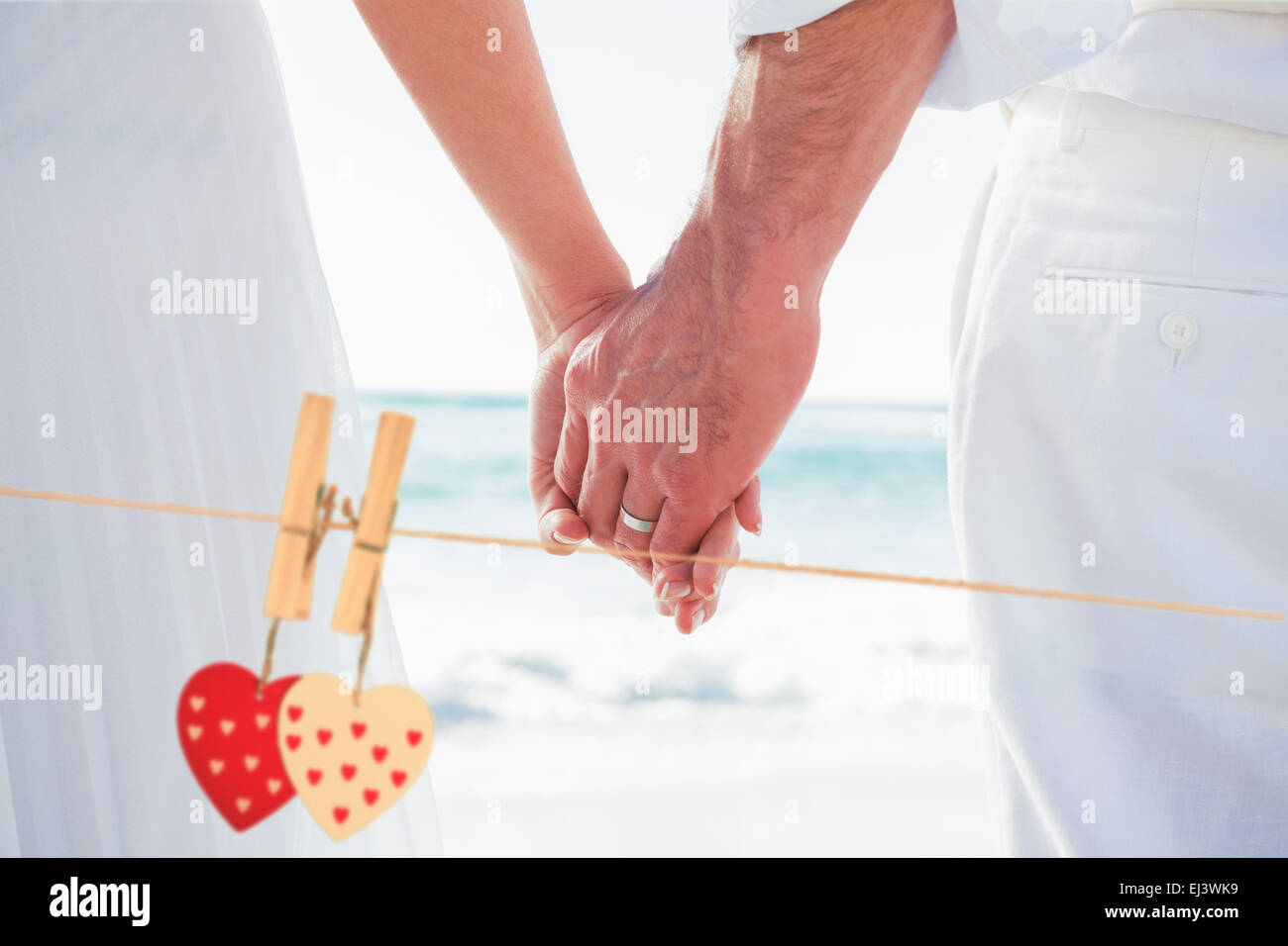 Composite image of bride and groom holding hands close up Stock Photo