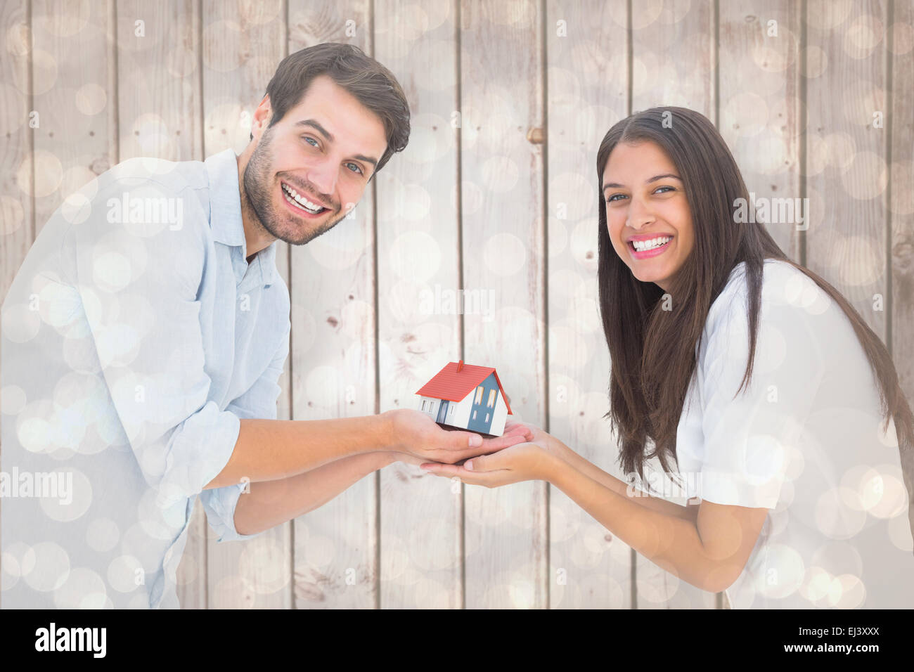 Composite image of attractive young couple holding a model house Stock ...