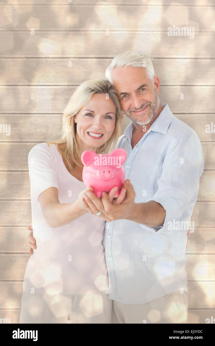 Composite image of happy couple showing their piggy bank Stock Photo ...