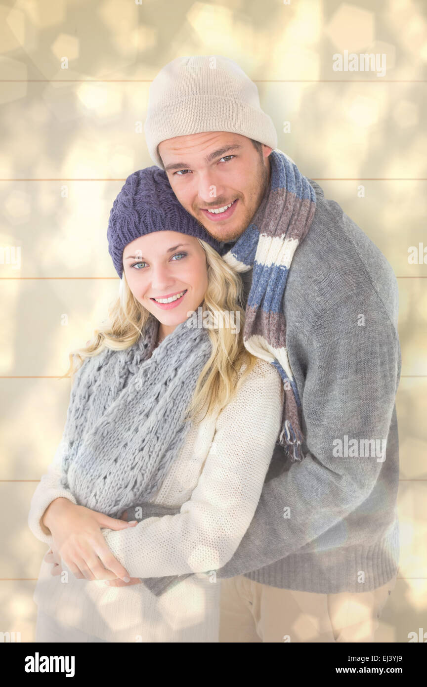 Composite image of attractive couple in winter fashion hugging Stock Photo