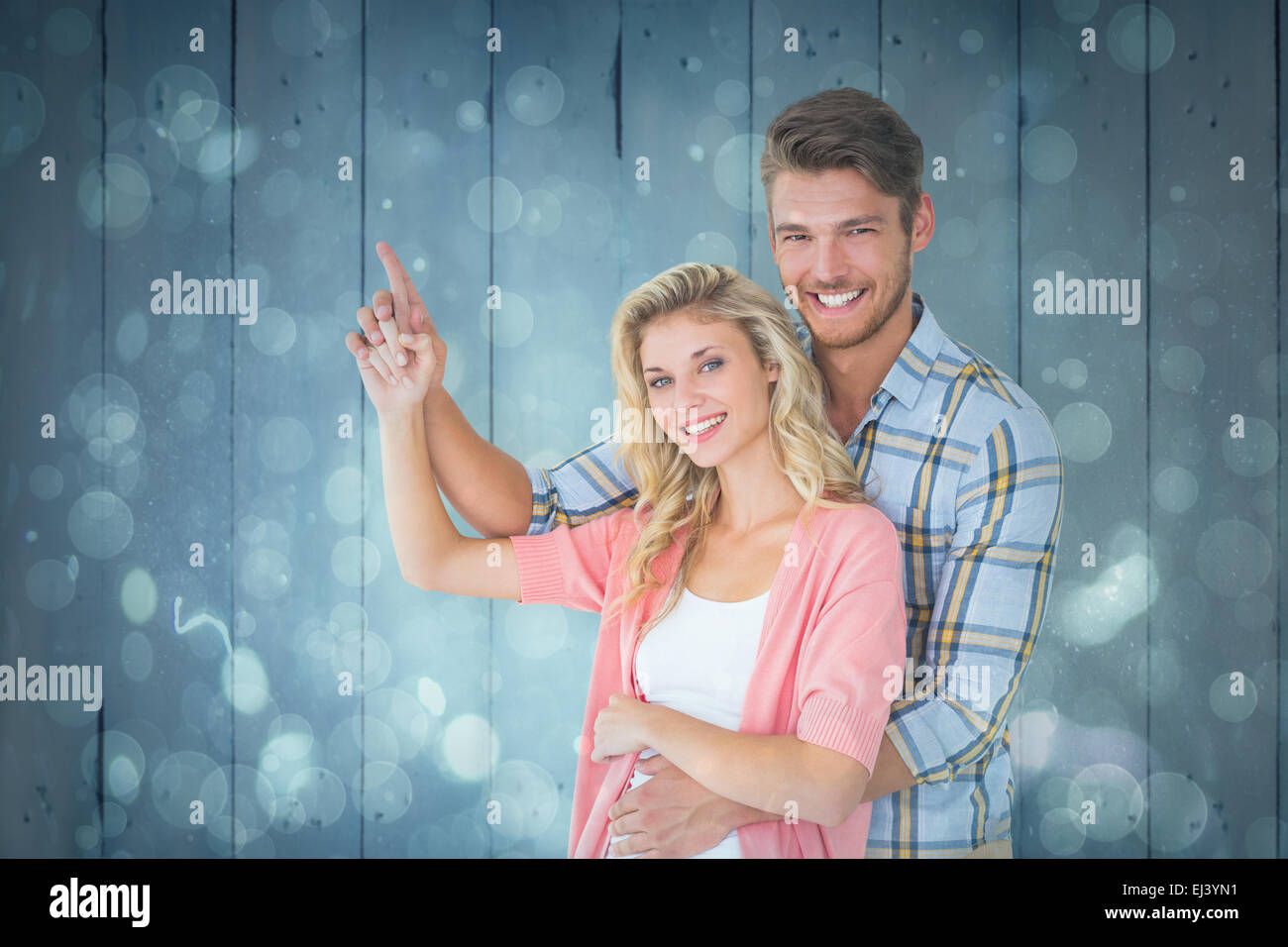 Composite image of attractive young couple embracing and pointing Stock Photo