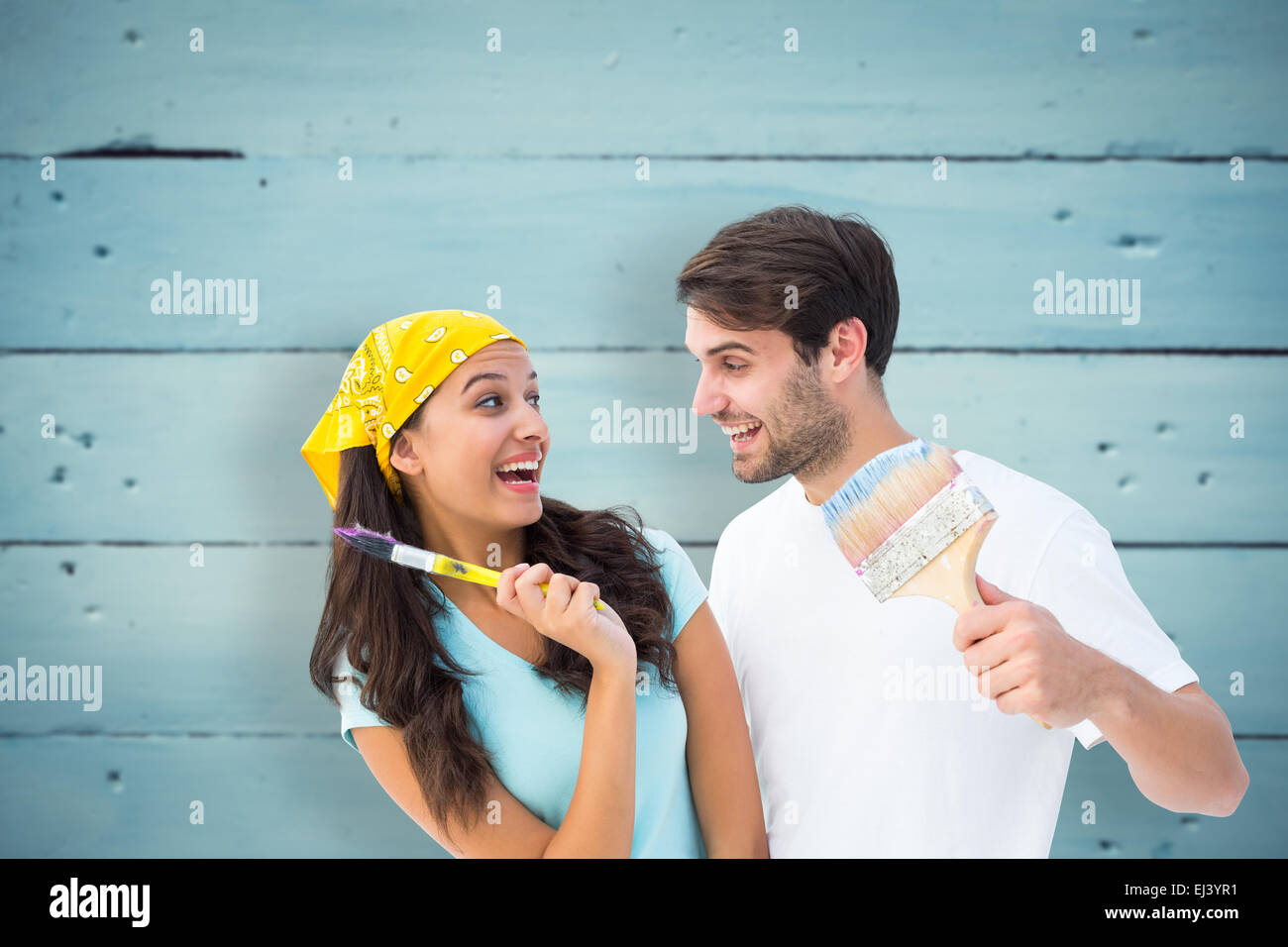 Composite image of happy young couple painting together and laughing Stock Photo