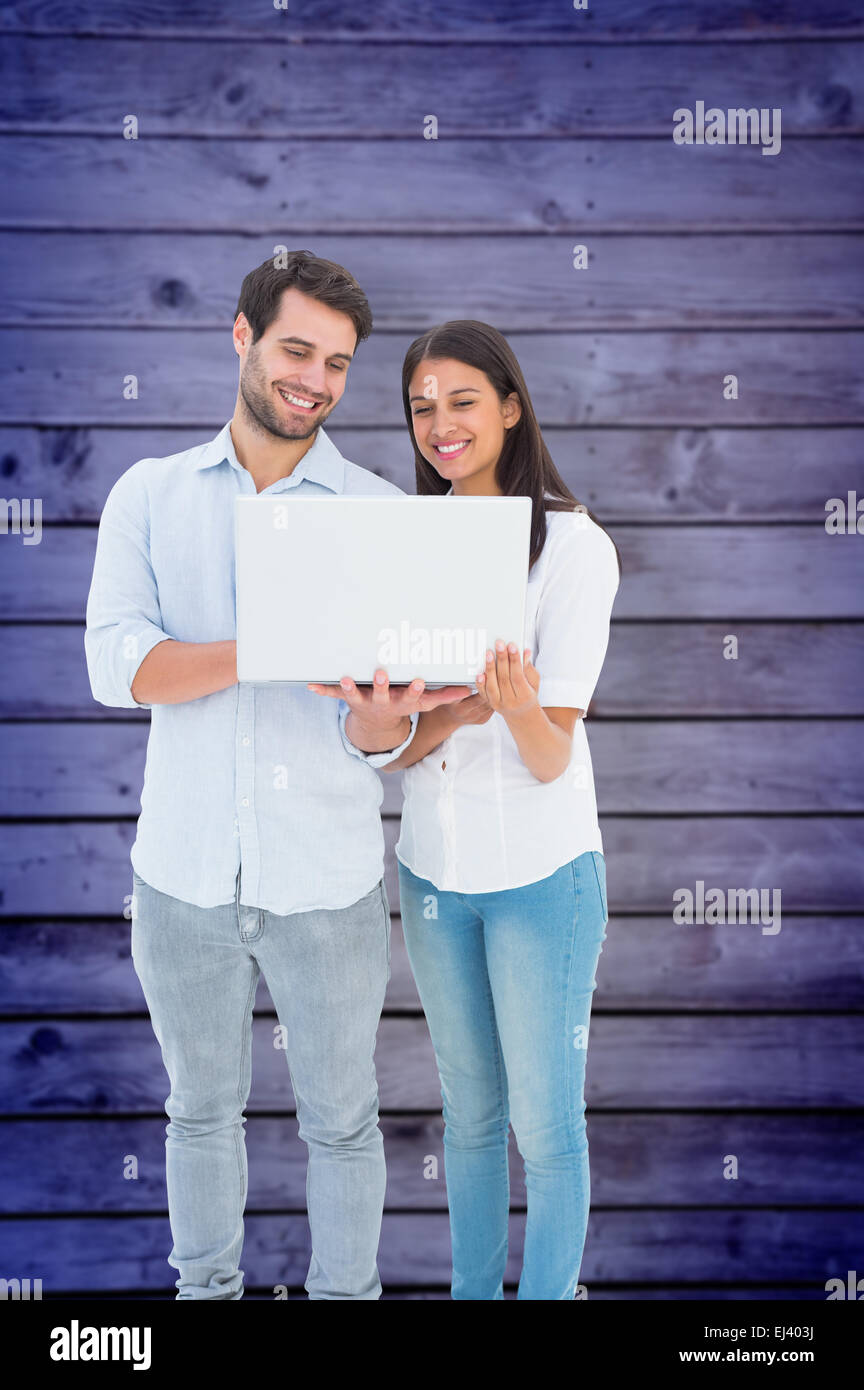 Composite image of attractive young couple holding their laptop Stock Photo