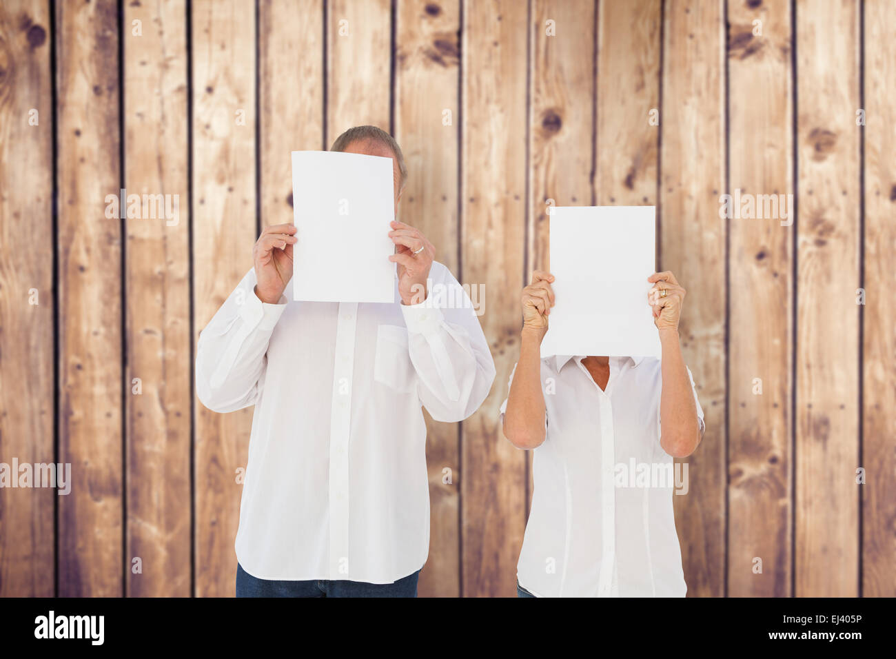 Composite image of couple holding paper over their faces Stock Photo