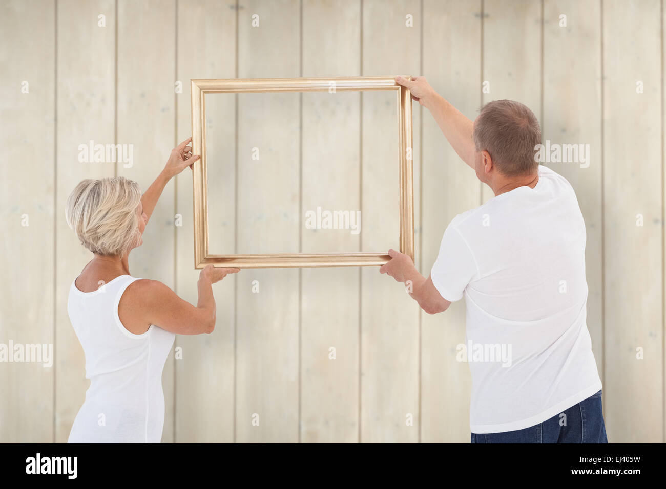 Composite image of mature couple hanging up picture frame Stock Photo
