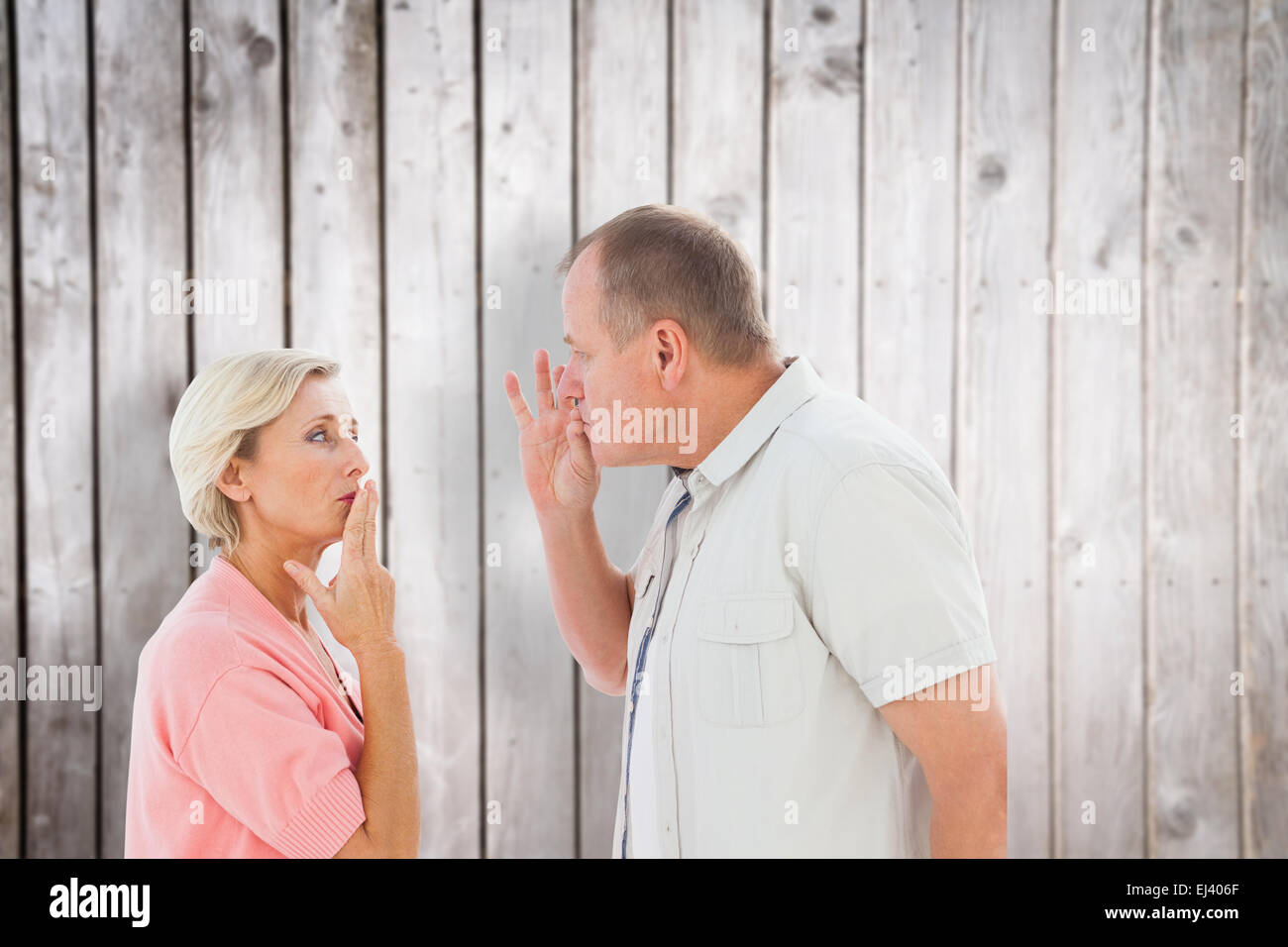 Composite image of older couple holding hands to mouth for silence Stock Photo