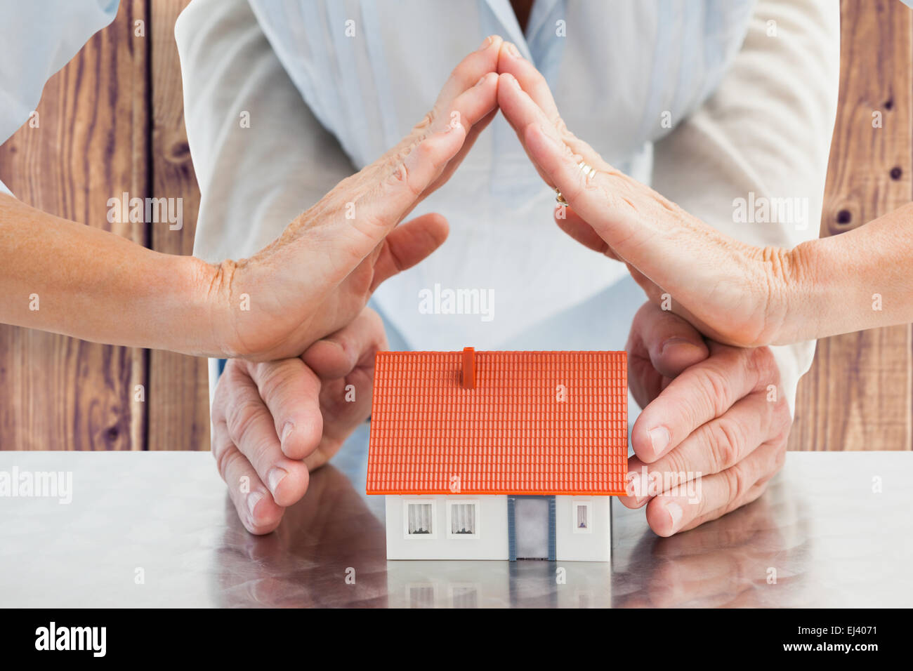 Composite image of couples hands with model house Stock Photo