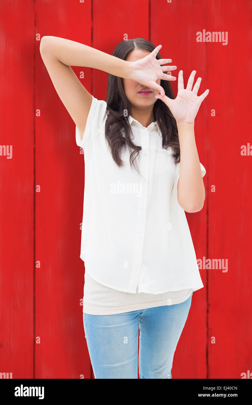 Composite image of fearful brunette covering her face Stock Photo