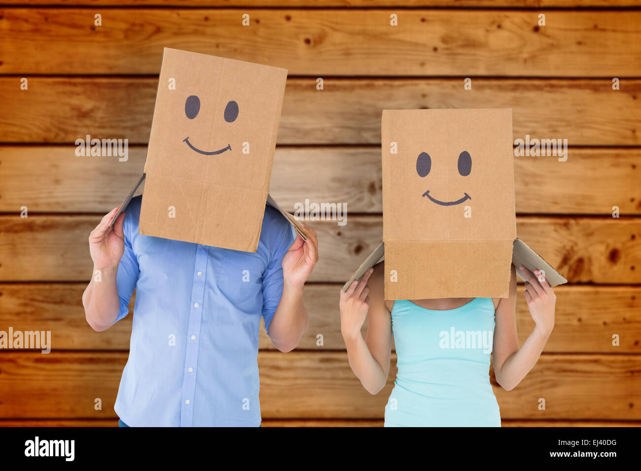Composite image of couple wearing emoticon face boxes on their heads Stock Photo