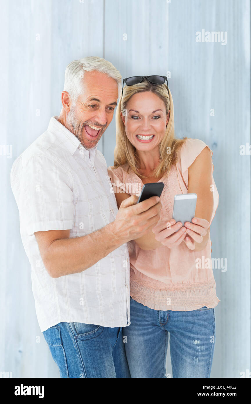 Composite image of happy couple looking at their smartphones Stock Photo