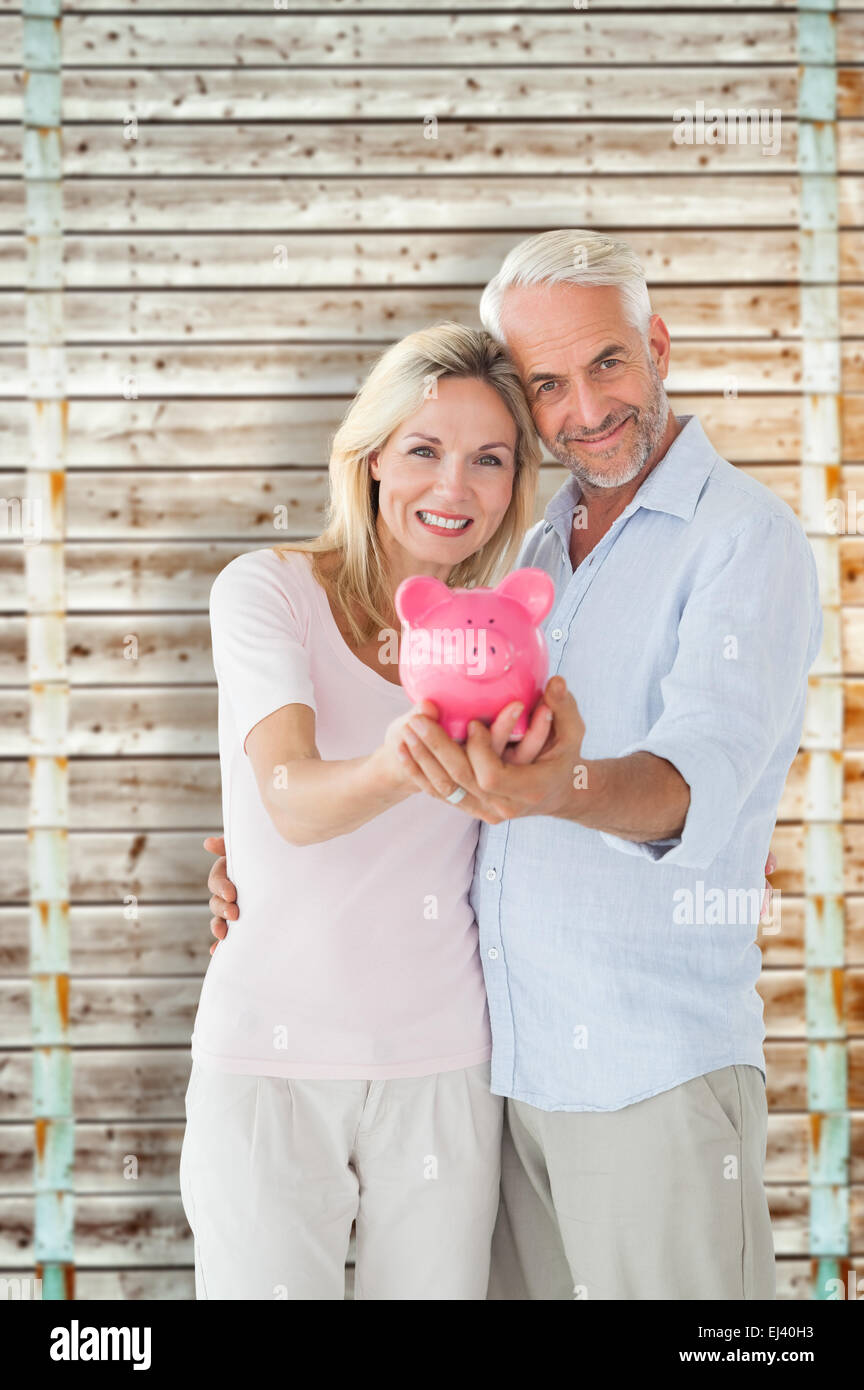 Composite image of happy couple showing their piggy bank Stock Photo ...
