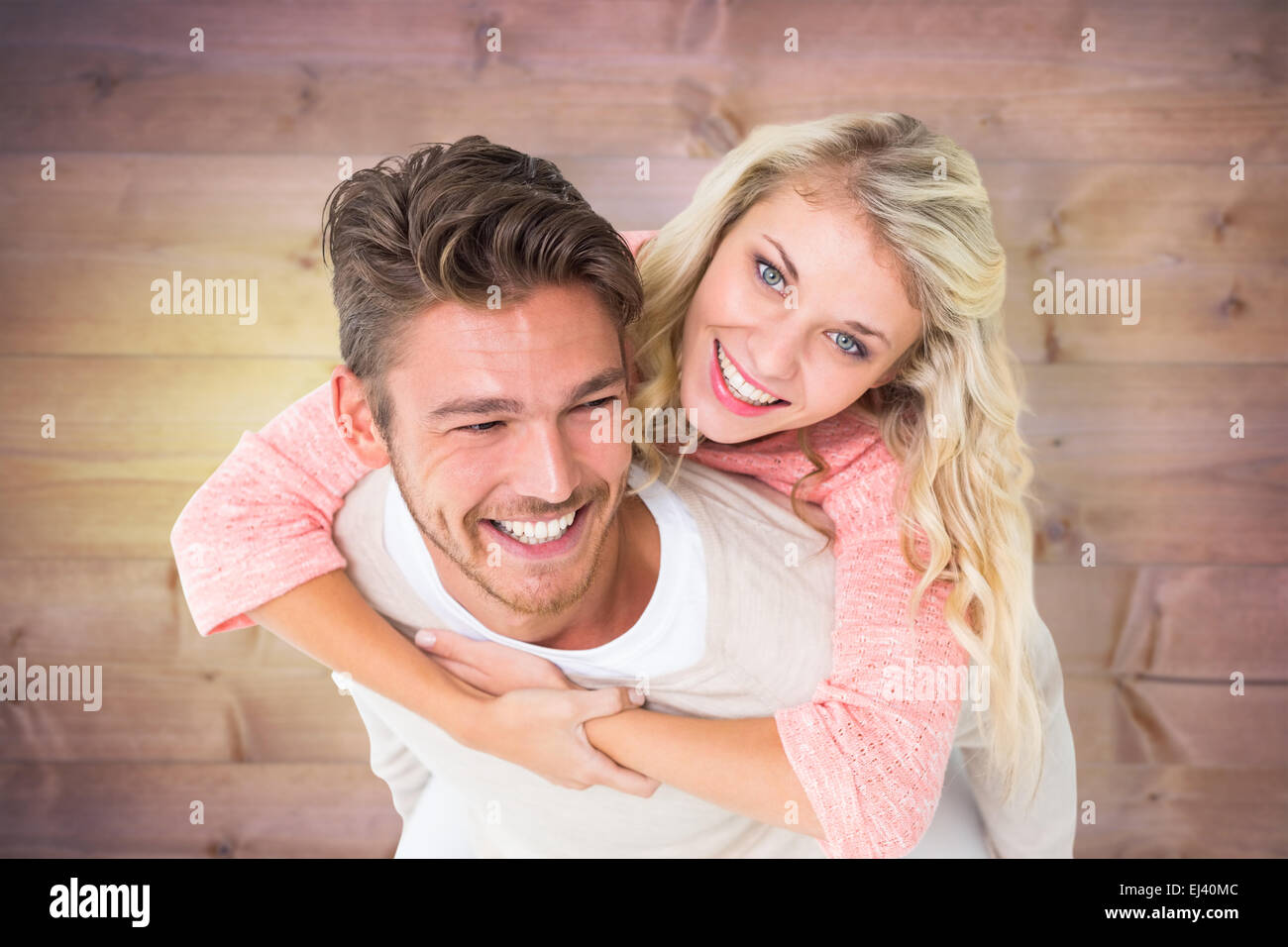 Composite image of handsome man giving piggy back to his girlfriend Stock Photo