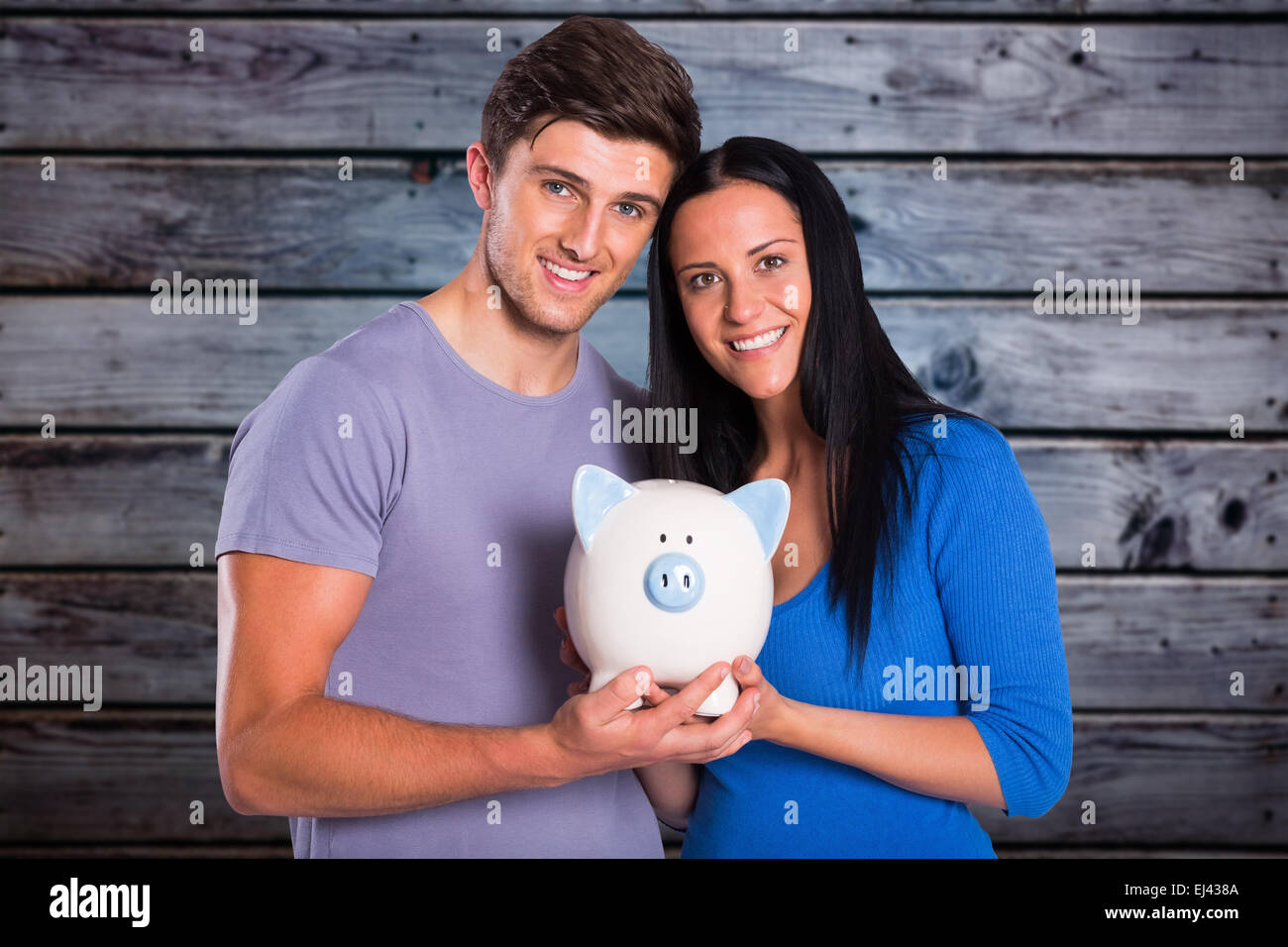 Composite image of young couple holding a piggy bank Stock Photo - Alamy