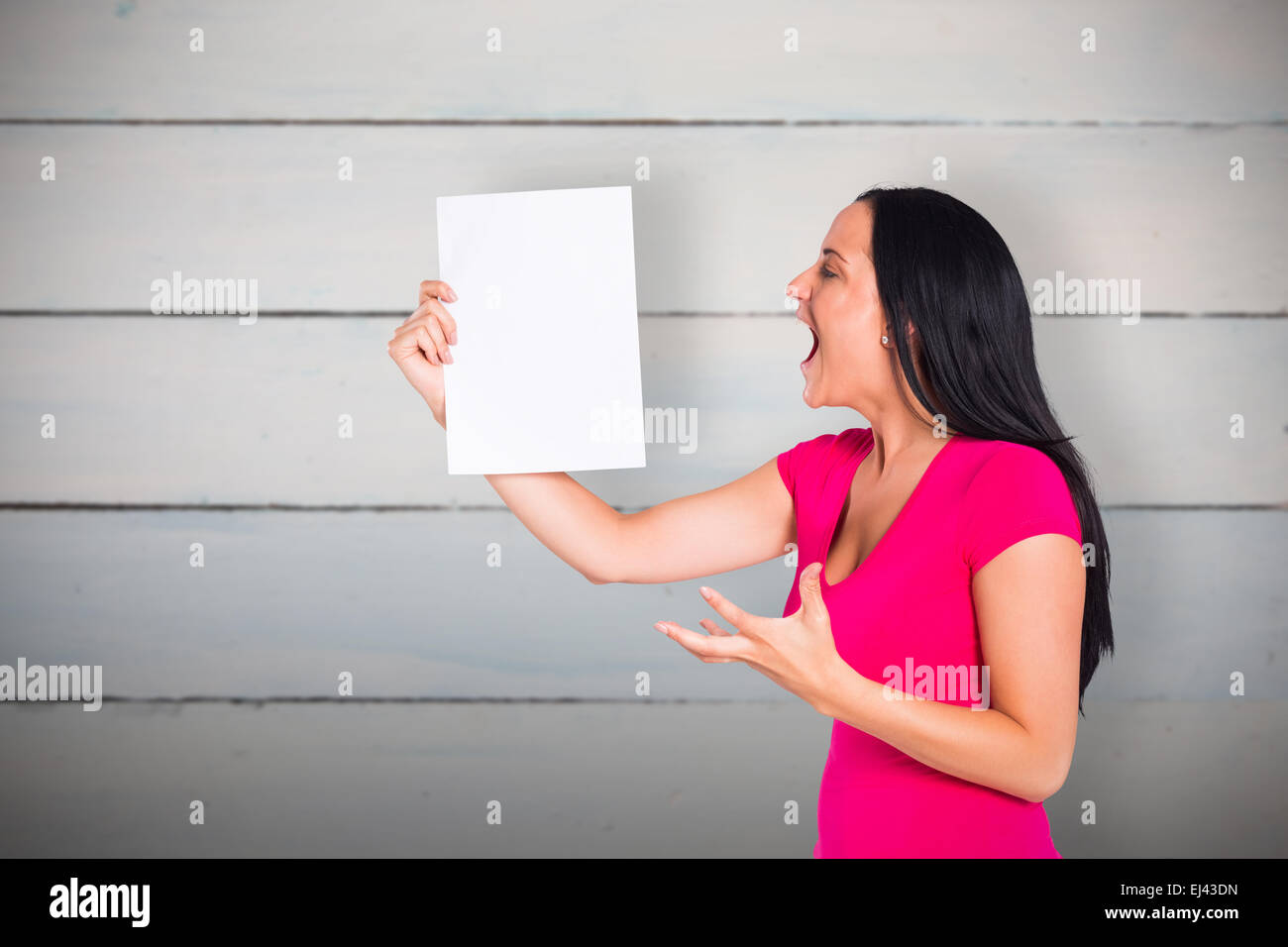 Composite image of angry woman shouting at piece of paper Stock Photo