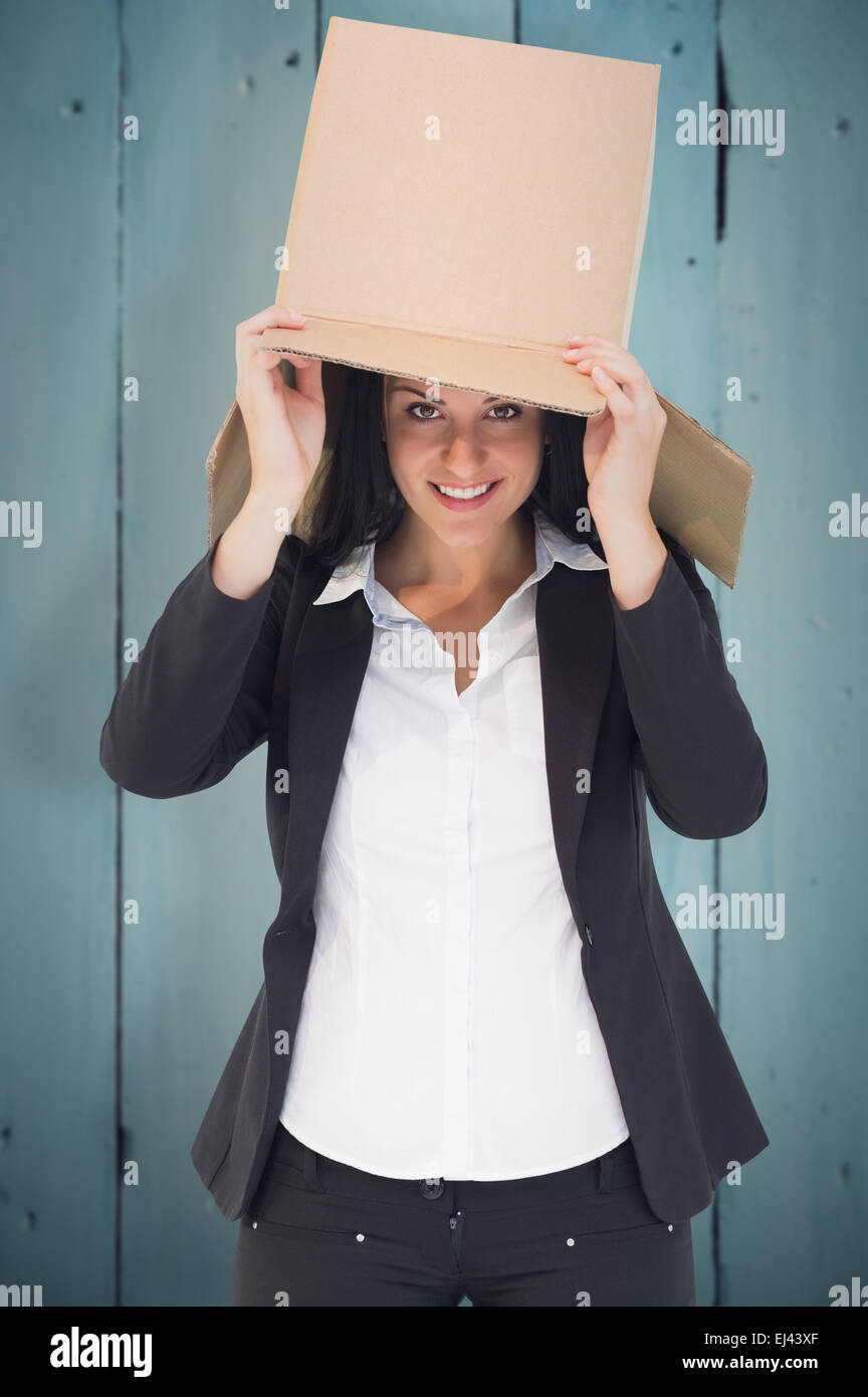Composite image of businesswoman lifting box off head Stock Photo