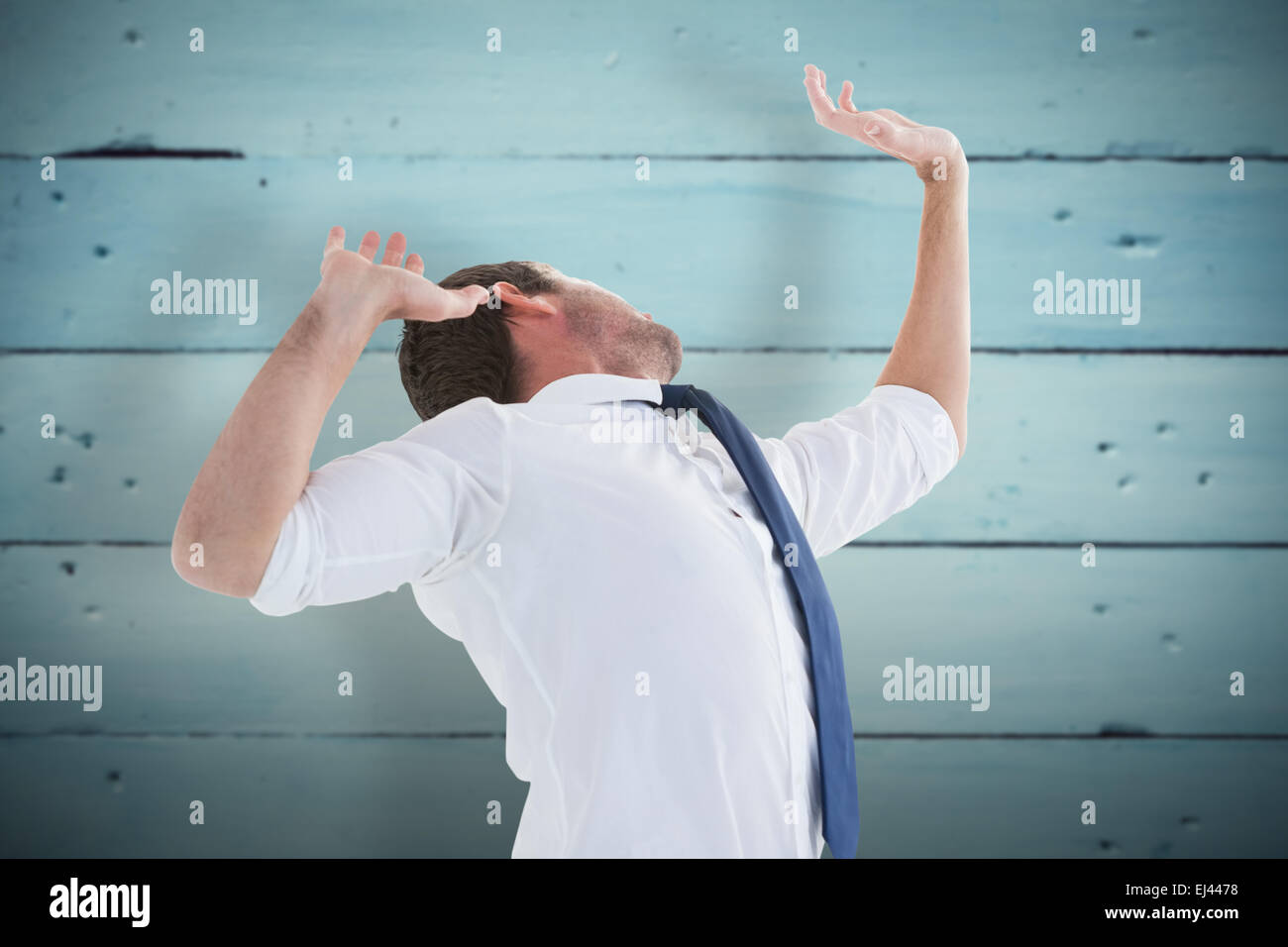 Composite image of businessman in suit with hands raised Stock Photo