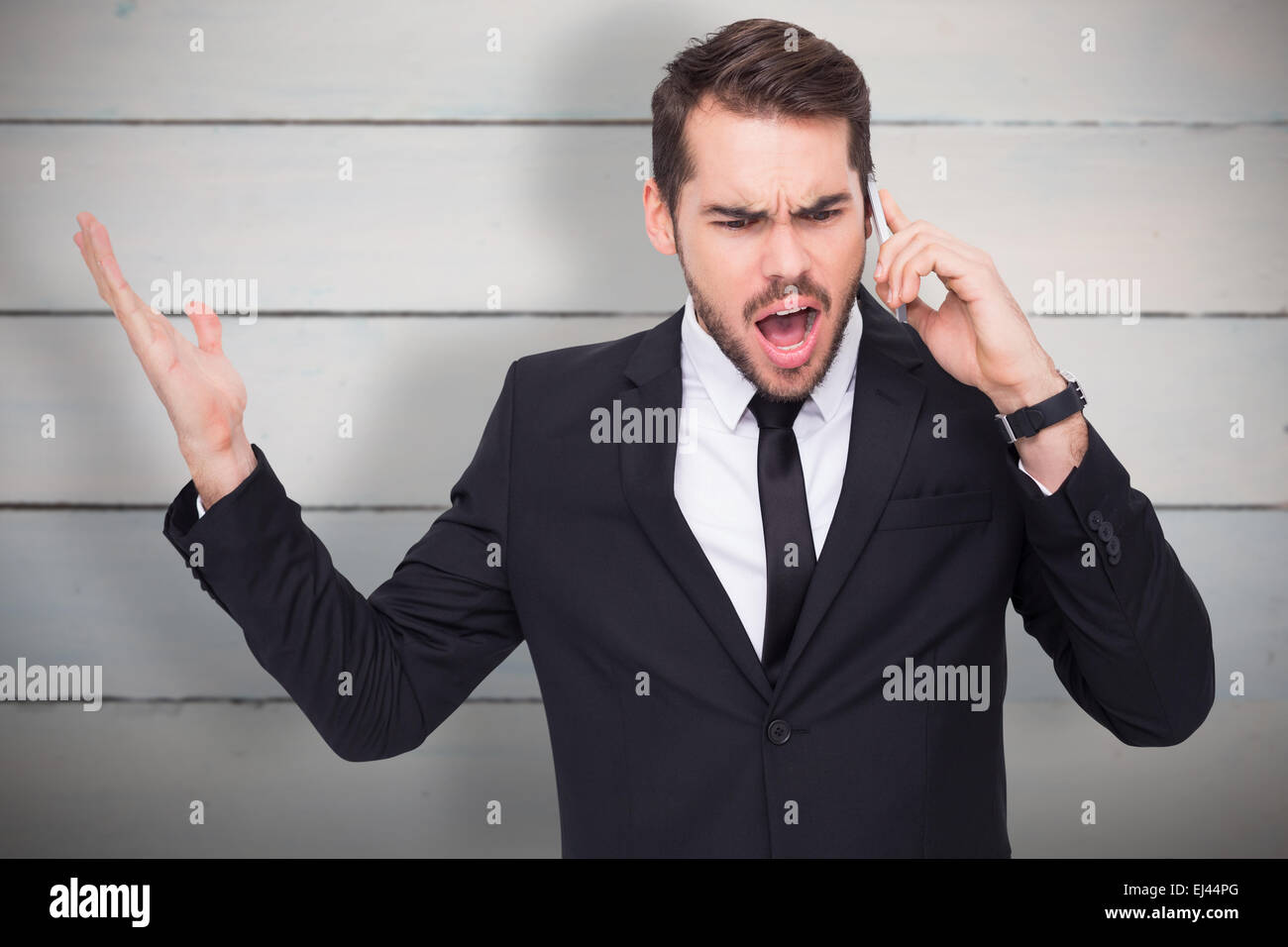 Composite image of angry businessman gesturing on the phone Stock Photo