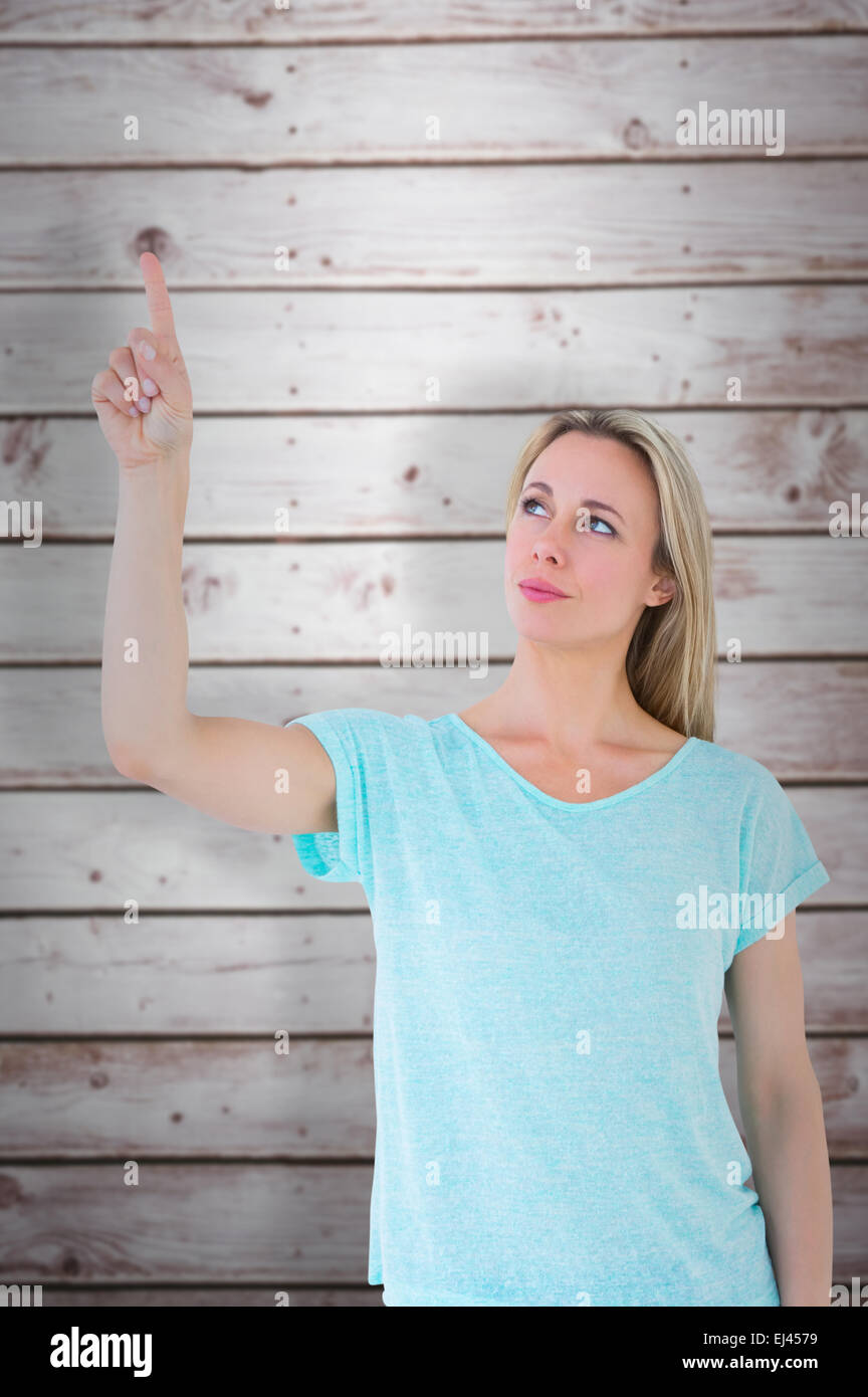 Composite image of pretty blonde thinking and pointing up Stock Photo