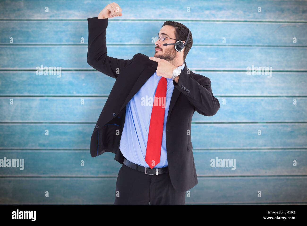 Composite image of smiling man wearing a headset while pointing his bicep Stock Photo