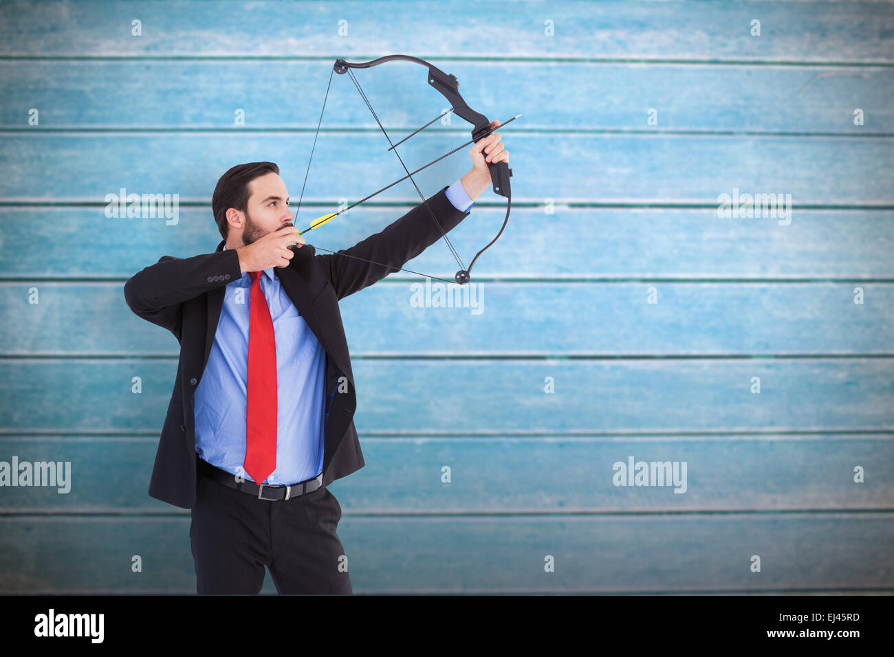 Composite image of focused businessman shooting a bow and arrow Stock Photo