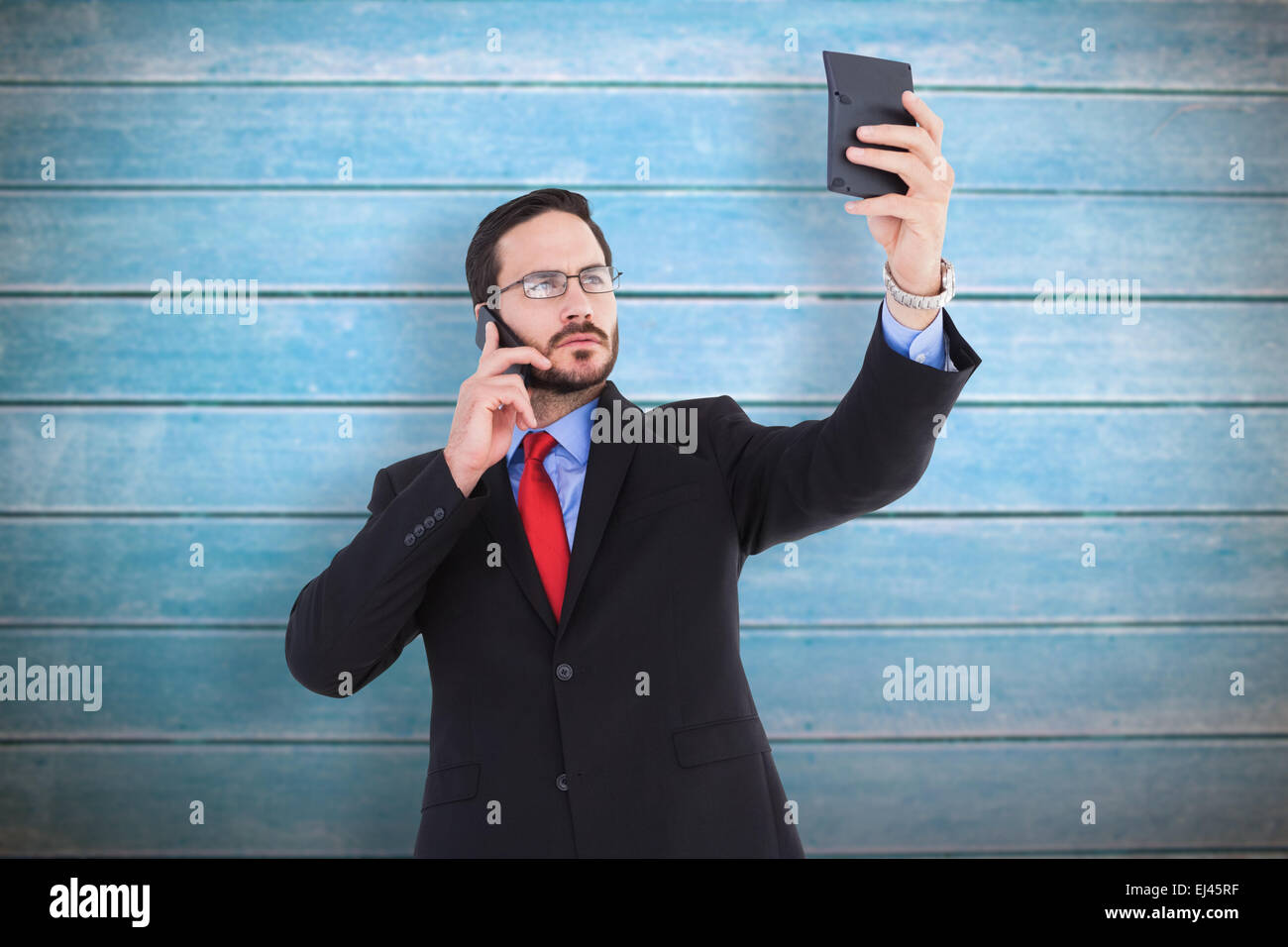 Composite image of businessman holding calculator while talking on phone Stock Photo