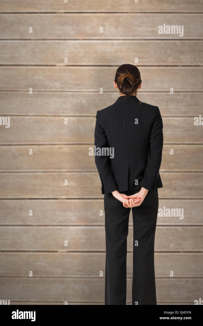 Composite image of businesswoman standing with hands behind back Stock Photo