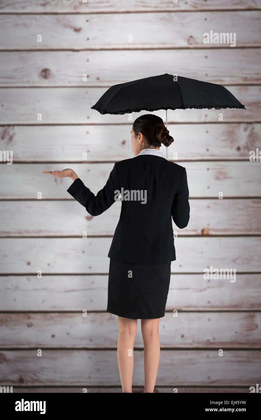 Composite image of young businesswoman holding umbrella Stock Photo