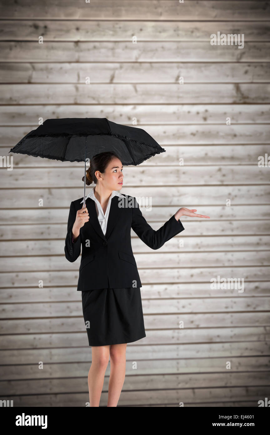 Composite image of young businesswoman holding umbrella Stock Photo